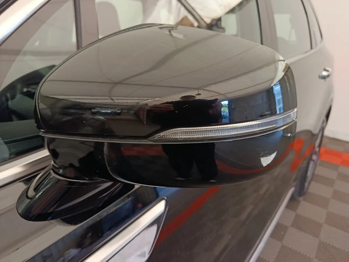 Gros plan sur le rétroviseur droit noir brillant du Kia Sorento 2023 hybride rechargeable, avec clignotant intégré.