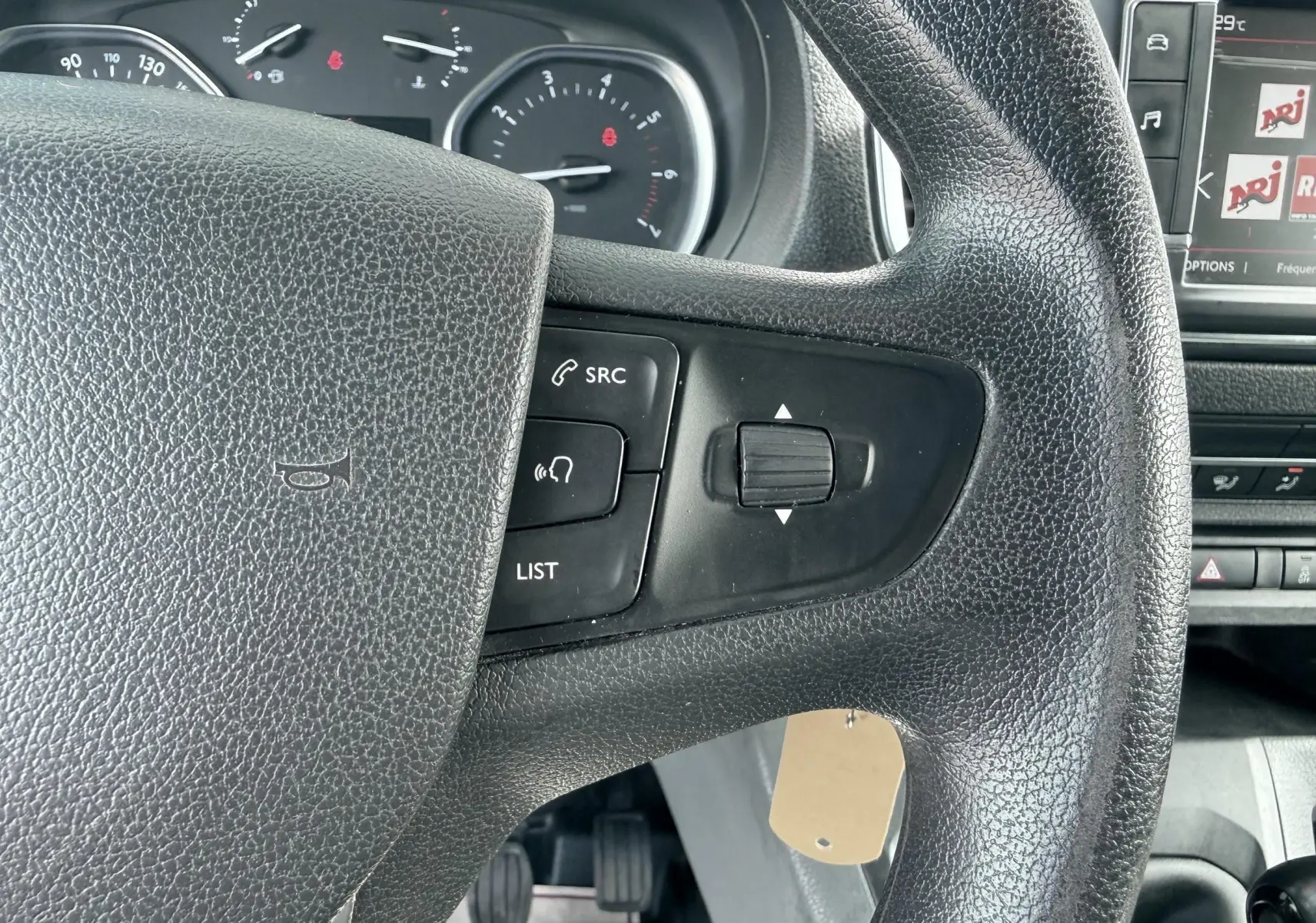 Gros plan sur le volant noir du Citroën Jumpy avec commandes intégrées, tableau de bord et écran multimédia partiellement visibles.