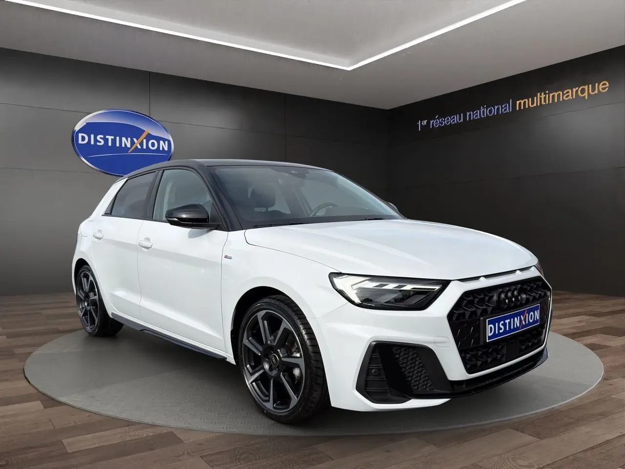 Audi A1 Sportback blanc en vue 3/4 avant droit, toit noir et jantes alliage noires distinctives.