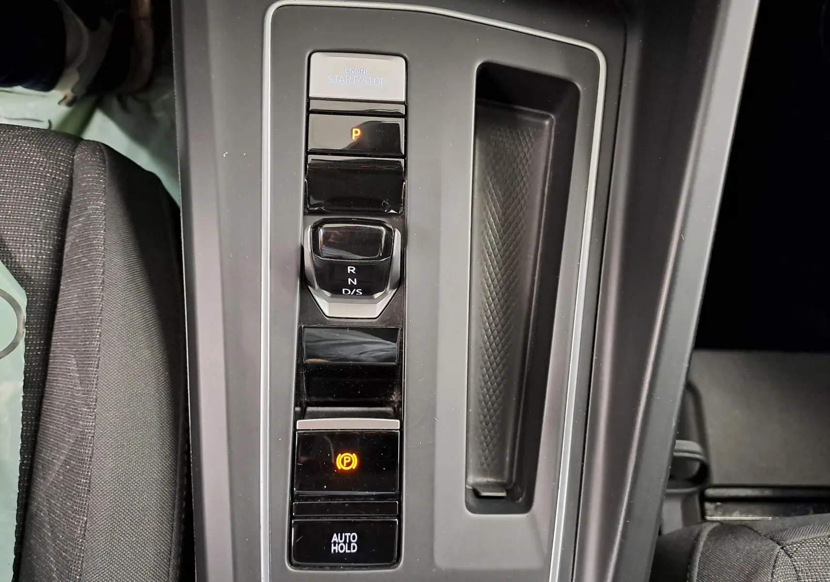 Gros plan sur la console centrale de la Volkswagen Golf blanche, montrant la commande de boîte automatique et frein électronique.