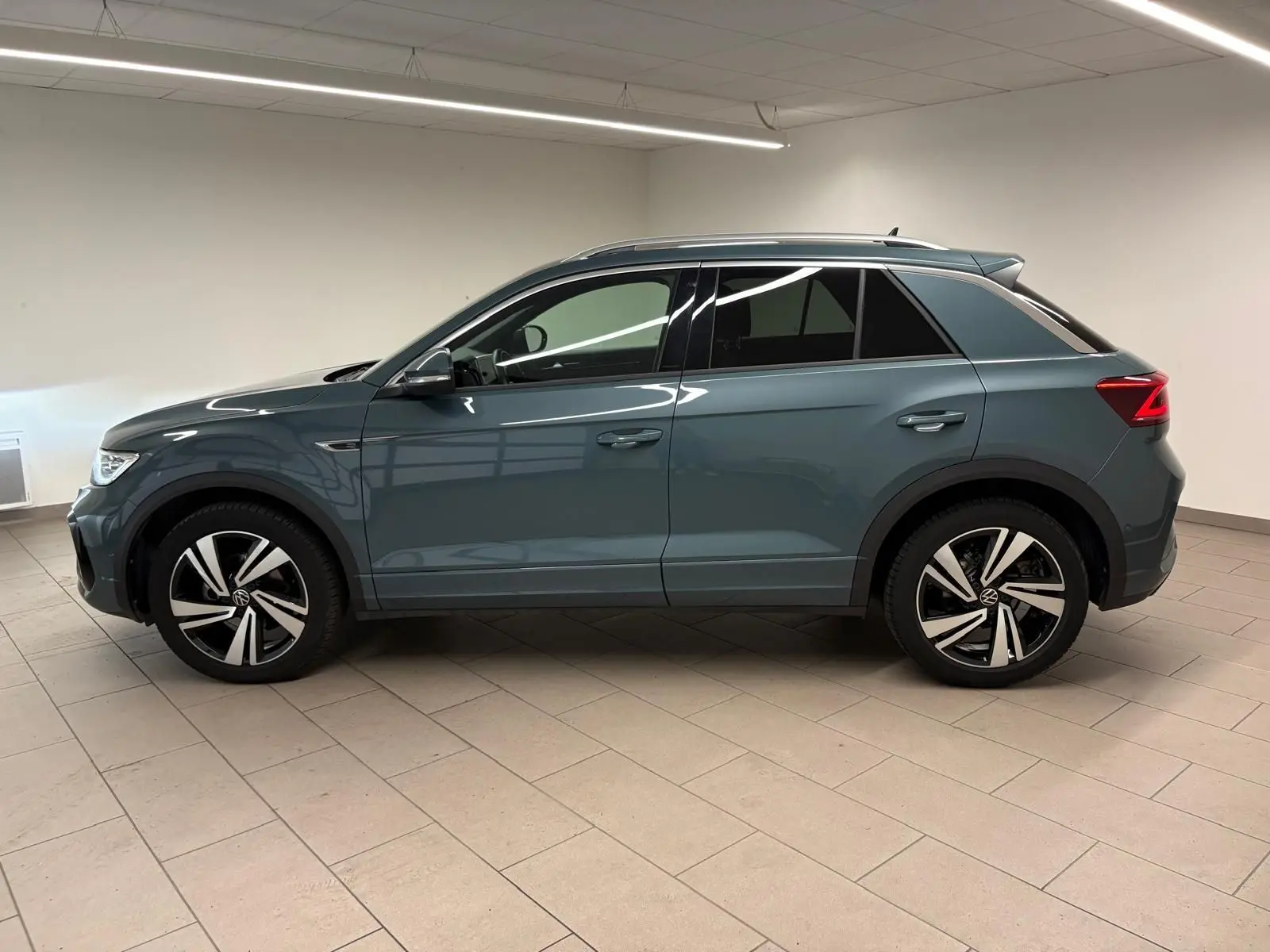 Volkswagen T-Roc 2024 bleu pétrole en vue profil côté gauche, avec jantes R-Line et vitres teintées.
