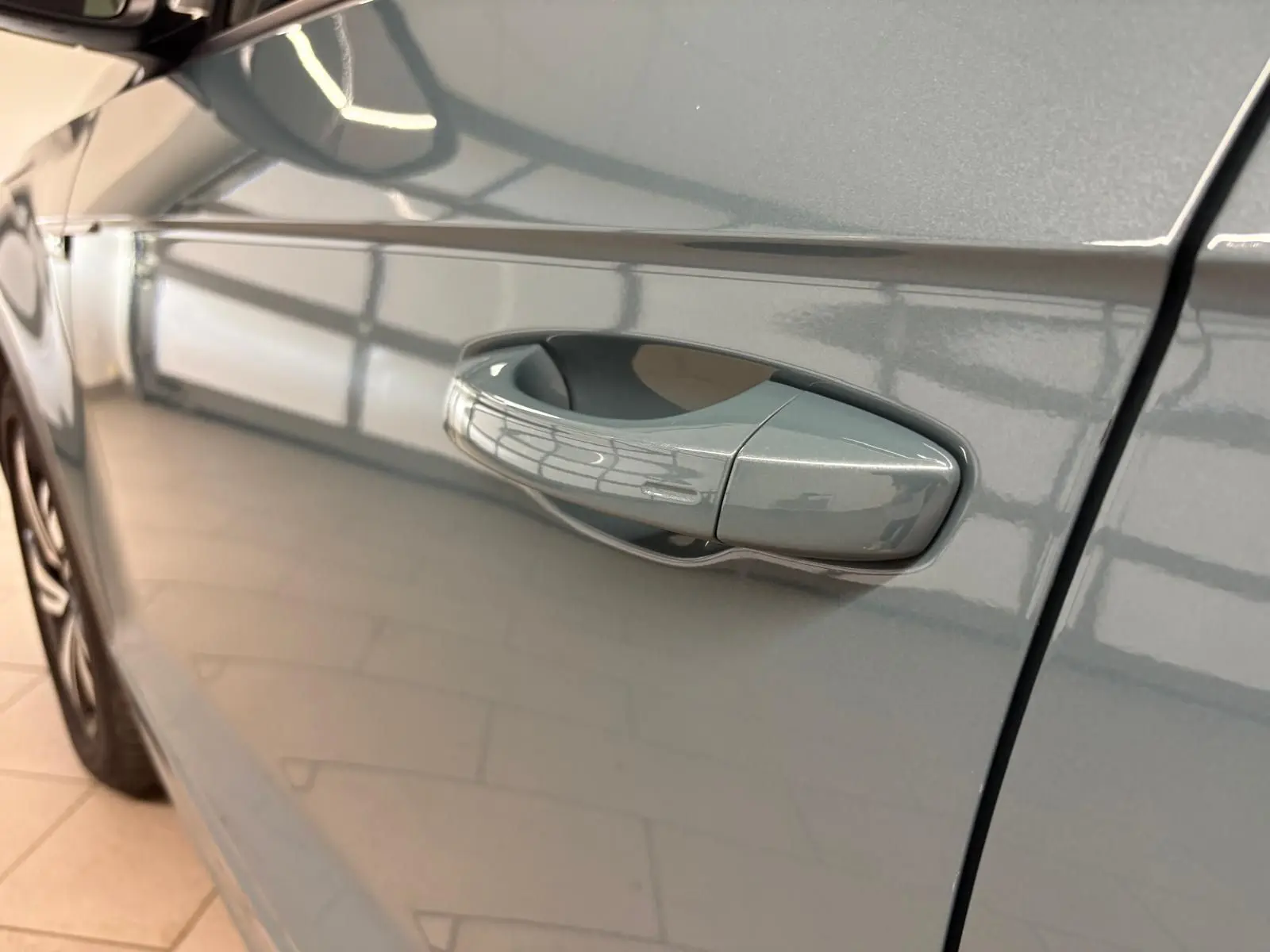 Poignée de porte côté gauche d'un Volkswagen T-Roc bleu pétrole 2024 avec peinture métallisée brillante.