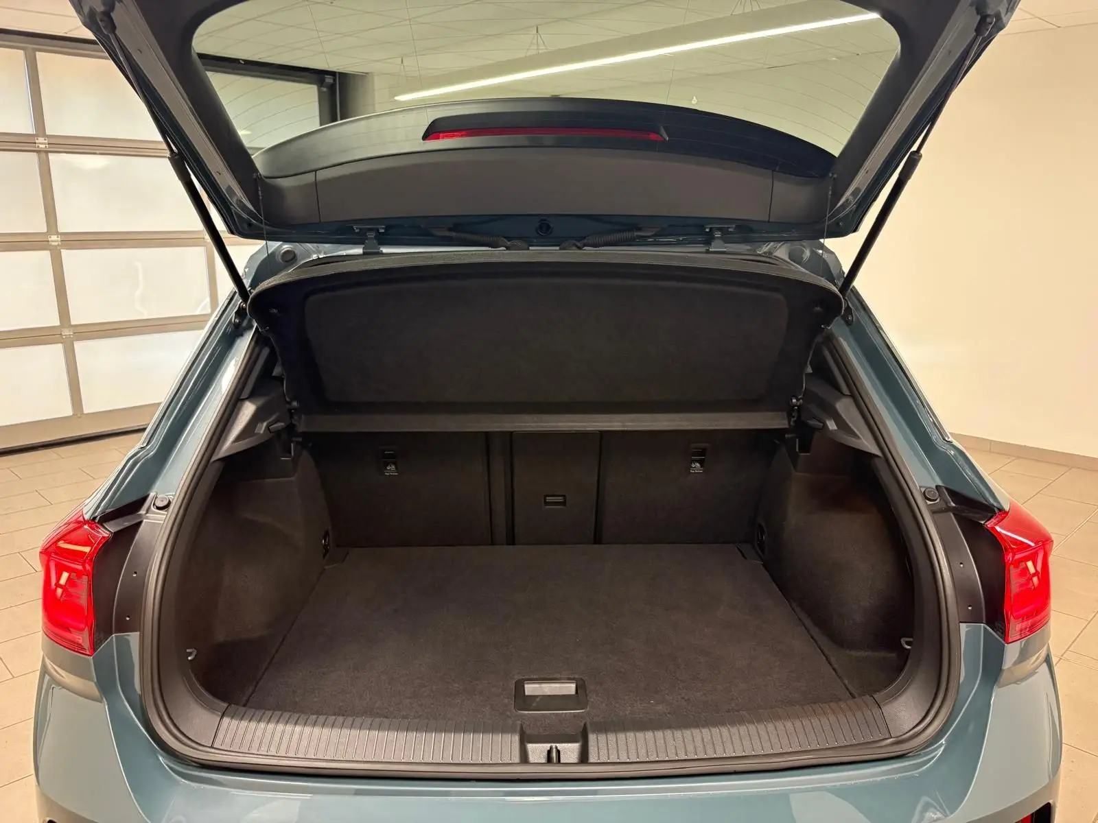 Coffre ouvert du Volkswagen T-Roc 2024 bleu pétrole vu de l'arrière, montrant un espace de chargement spacieux et propre.
