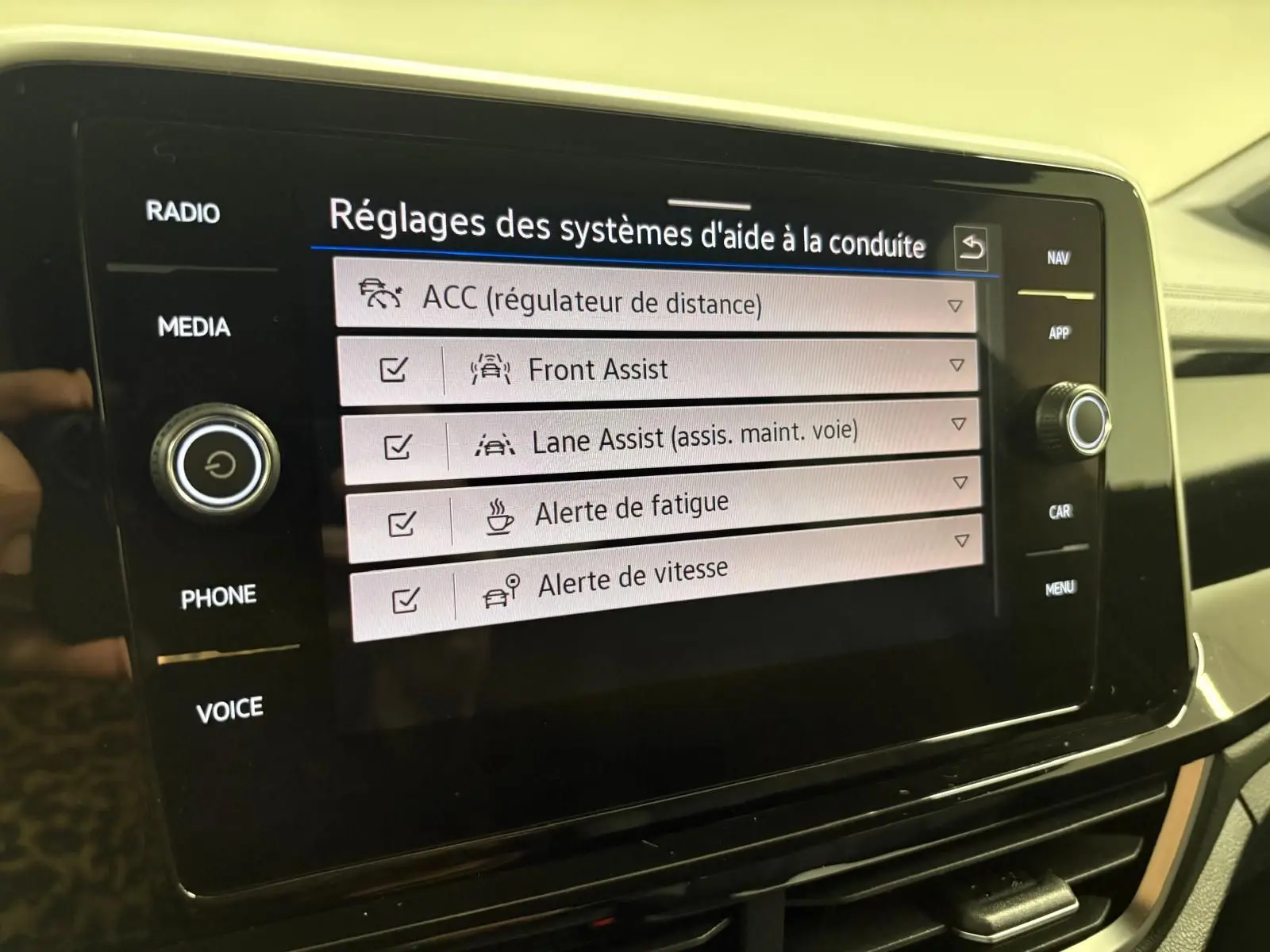 Écran tactile du système d'infodivertissement du Volkswagen T-Roc 2024 affichant les réglages d'aide à la conduite.