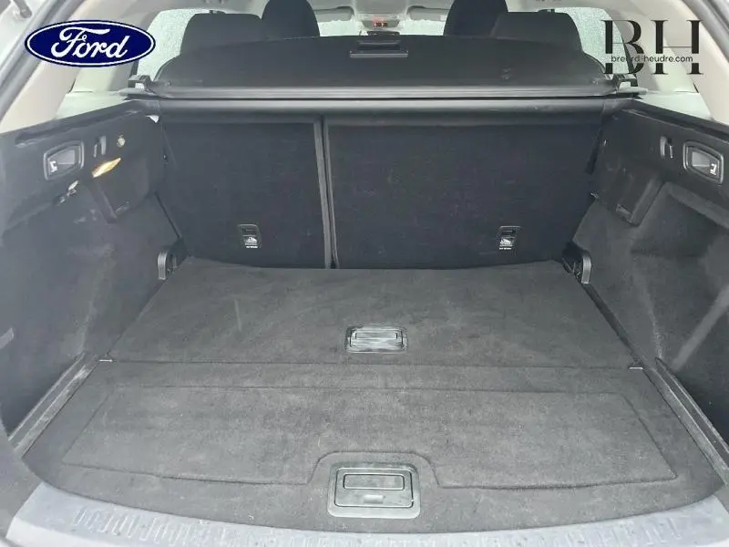 Coffre ouvert vu de l'arrière d'une Renault Mégane Break gris platine, espace de chargement spacieux et tapis noir.