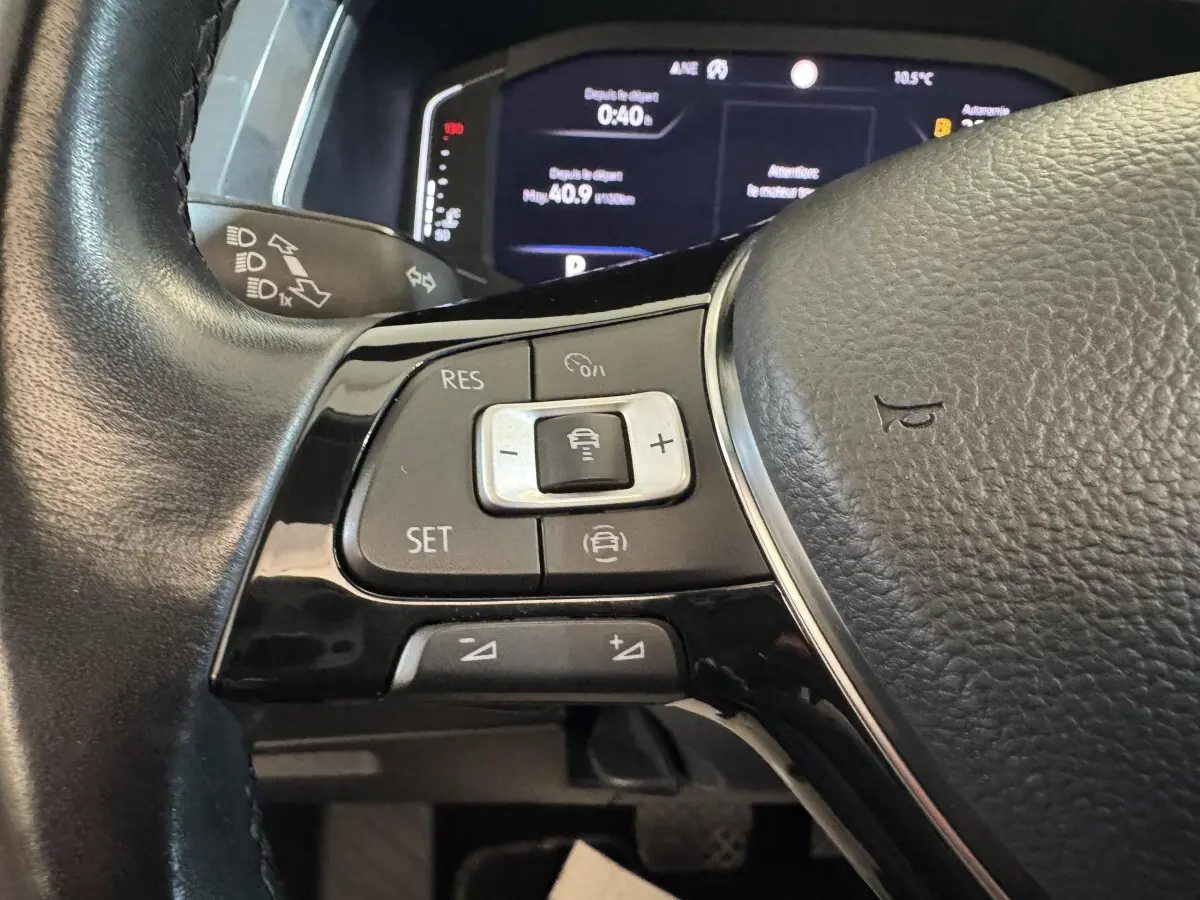 Gros plan sur les commandes du volant cuir noir du Volkswagen Tiguan Allspace 2019, avec affichage numérique en arrière-plan.