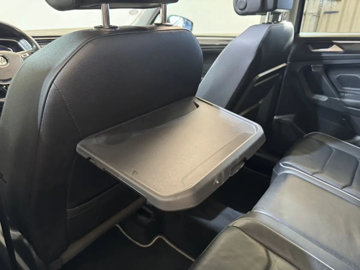 Vue intérieure côté droit du Volkswagen Tiguan Allspace 2019, tablette rabattable sur siège avant noir en cuir.