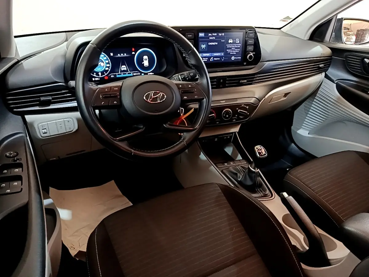 Intérieur Hyundai i20 2022 vu de face, volant cuir multifonctions, écran tactile et boîte manuelle noire.