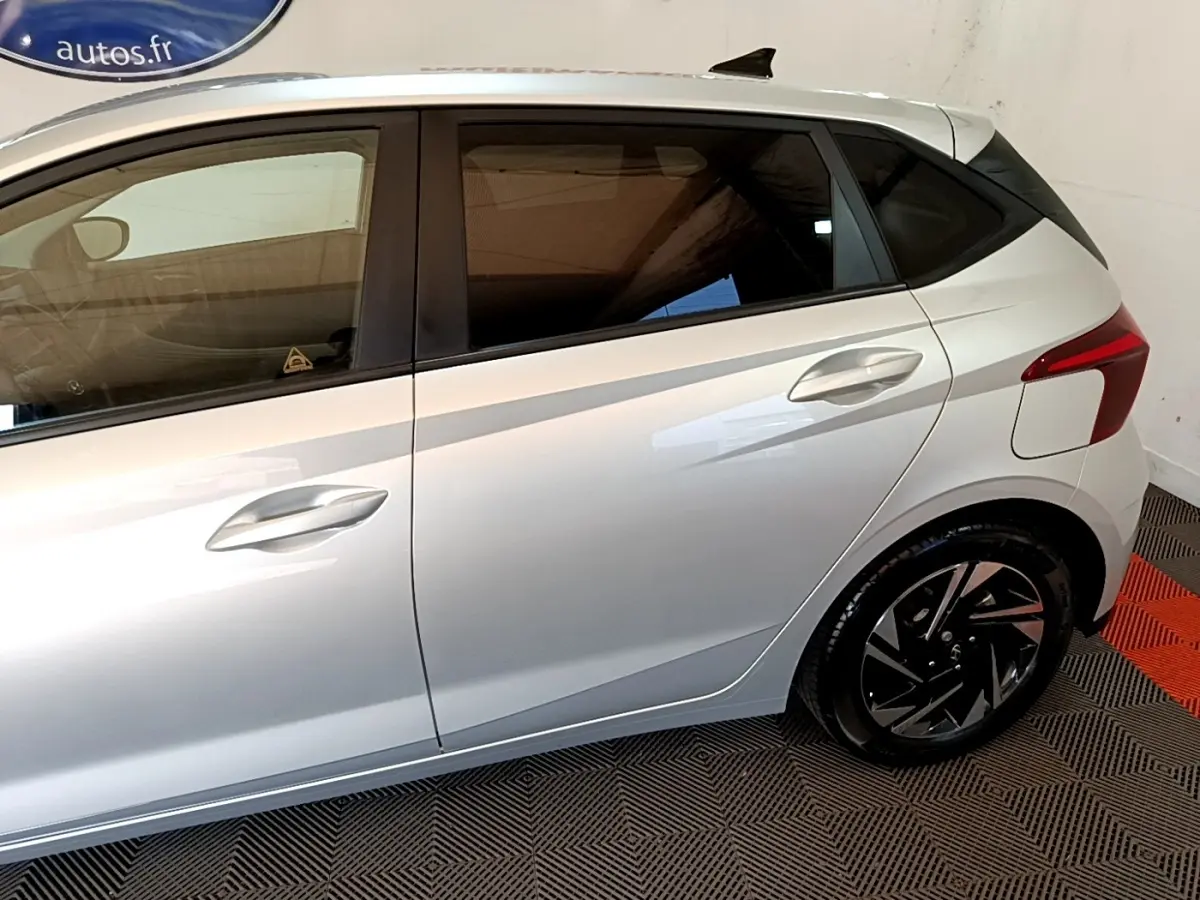 Vue latérale droite d'une Hyundai i20 gris clair 2022 avec jantes noires et vitres teintées.