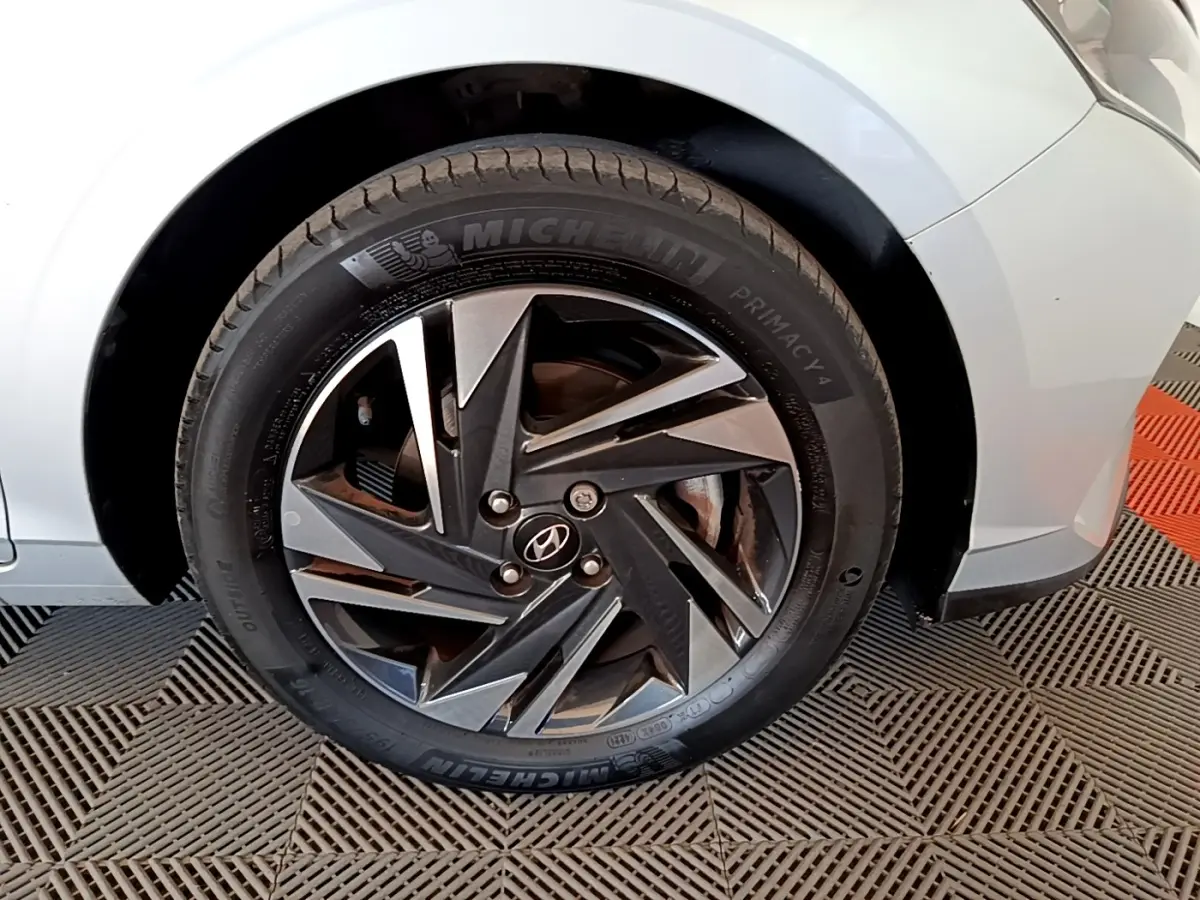 Gros plan sur la roue avant gauche gris clair d'une Hyundai i20 2022 avec jante alliage noire et argentée.