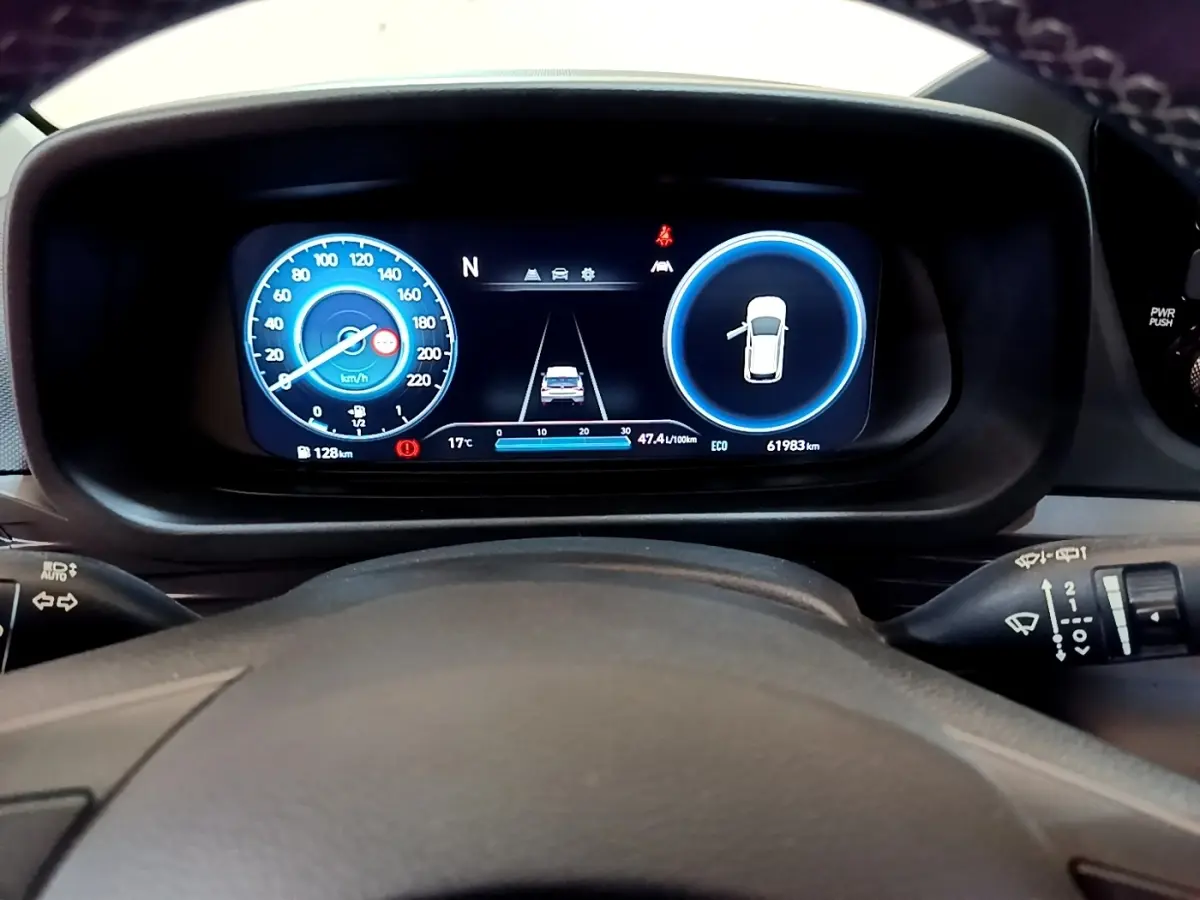 Vue rapprochée du tableau de bord numérique de la Hyundai i20 hybride 2022, affichage vitesse et alertes sur fond noir.