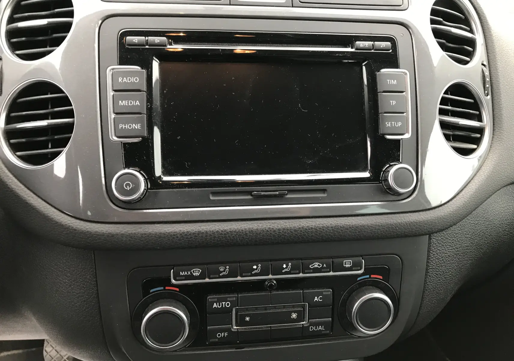 Vue rapprochée du tableau de bord noir du Volkswagen Tiguan Sportline 2012 avec écran tactile et commandes de climatisation.