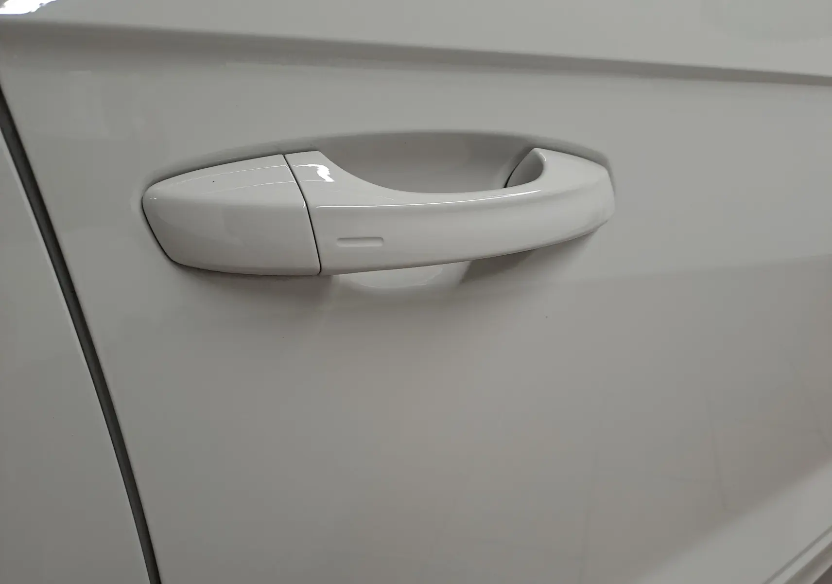 Poignée de porte blanche en gros plan sur la portière côté gauche d'un Volkswagen T-Roc 2024 Gris Ascot.