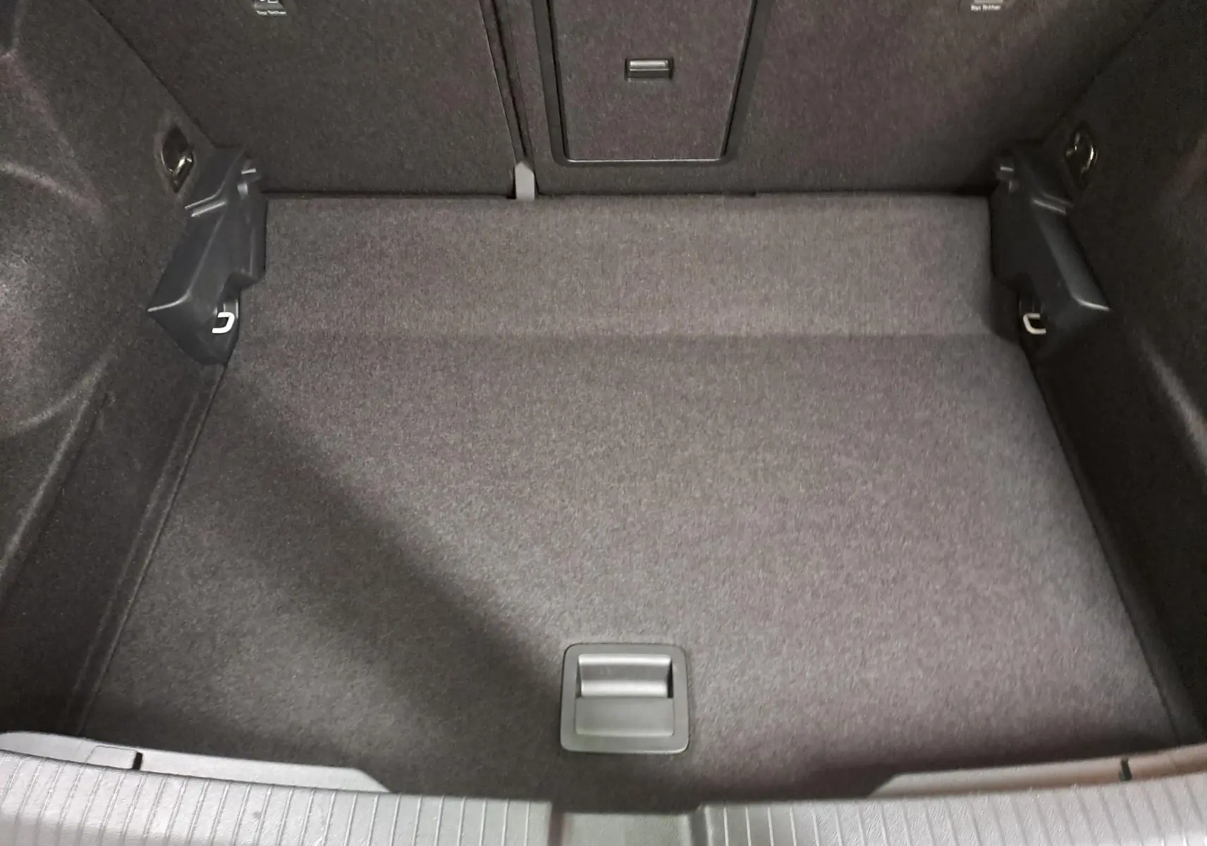 Coffre vide du Volkswagen T-ROC 1.5 TSI 150 DSG7 R-LINE 2024, vue plongeante sur le tapis gris foncé.