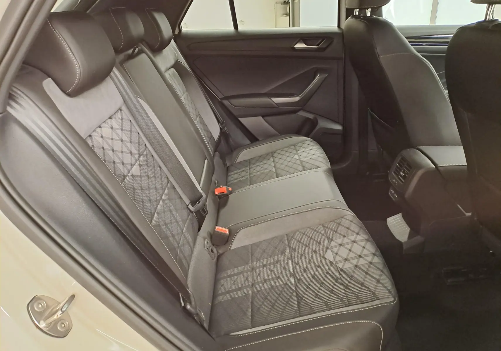 Vue côté gauche des sièges arrière en tissu gris à motif quadrillé du Volkswagen T-ROC 1.5 TSI R-Line 2024.