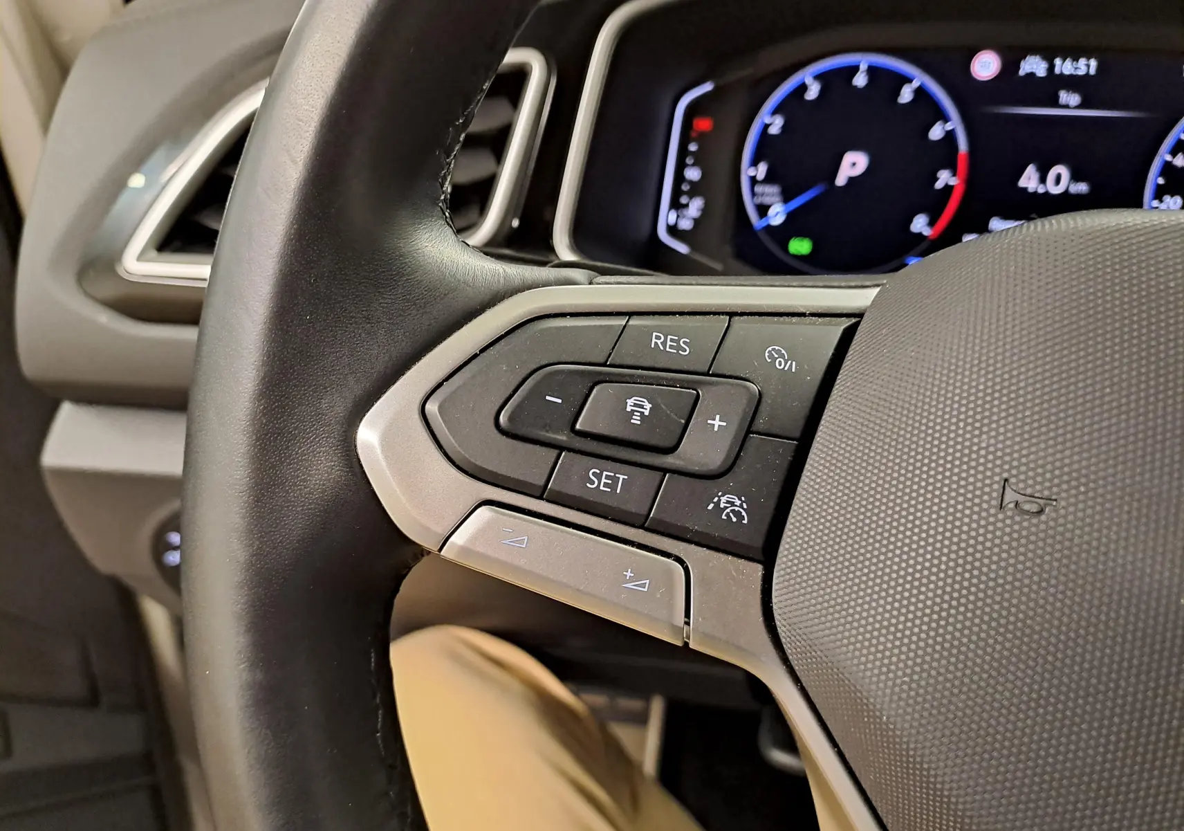 Gros plan sur le volant à gauche du Volkswagen T-Roc 2024, avec commandes de régulateur et tableau de bord numérique.