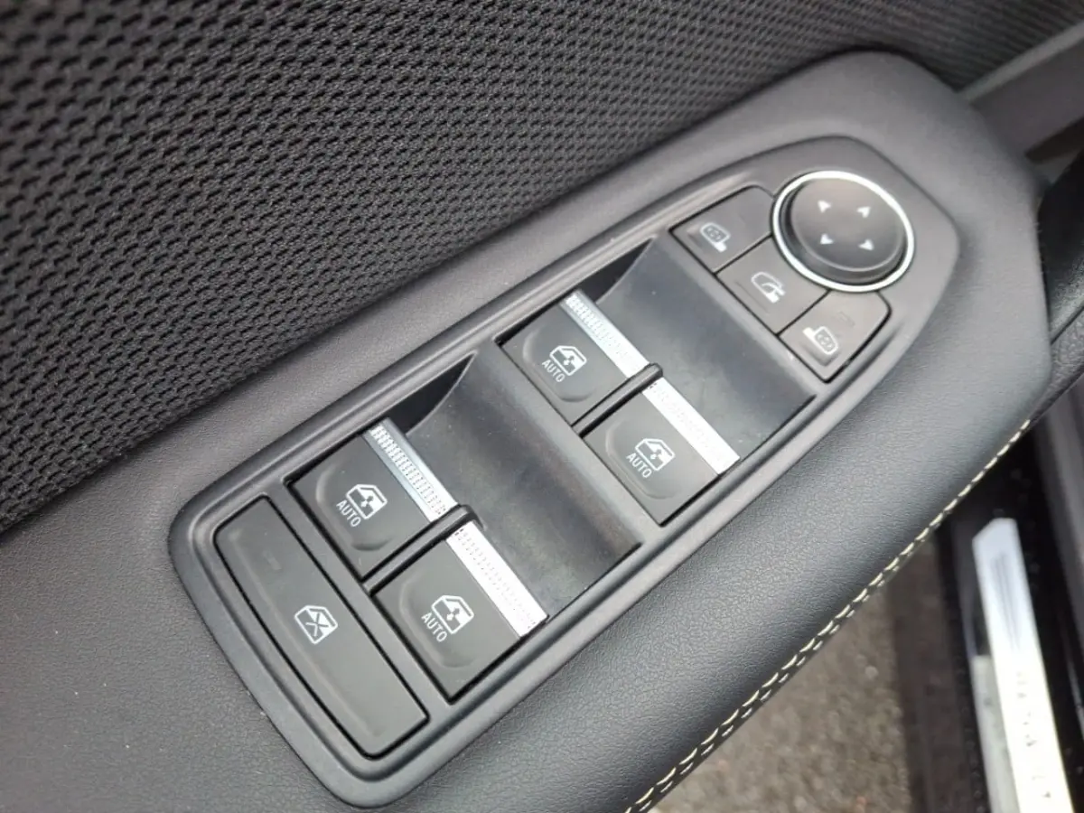 Gros plan sur les commandes de lève-vitres et rétroviseurs sur la porte côté conducteur d’une Renault Symbioz noire.