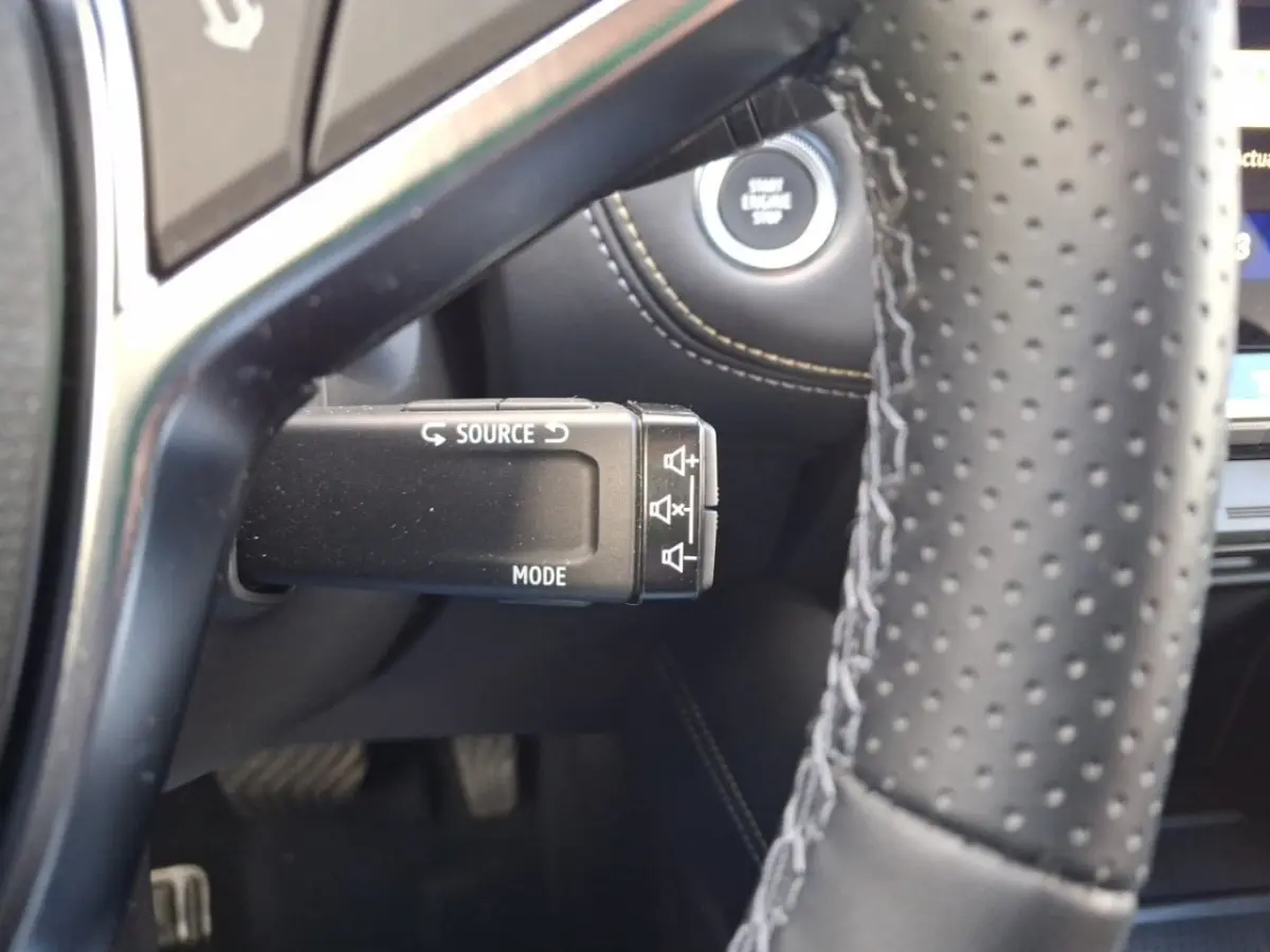 Gros plan sur la commande multifonction noire côté gauche du volant perforé du Renault Symbioz noir, avec bouton démarrage visible.