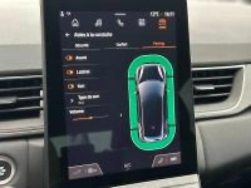 Écran tactile intérieur du Renault Captur 2025 affichant l'aide au stationnement et les capteurs autour du véhicule.
