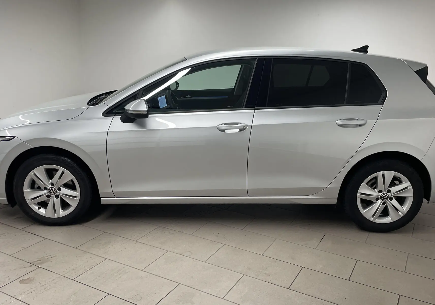 Volkswagen Golf 2022 en peinture métallisée reflet d'argent vue de profil côté gauche dans un intérieur neutre.