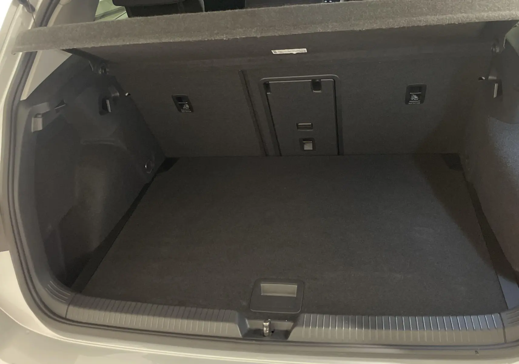 Coffre ouvert d'une Volkswagen Golf 2.0 TDI 115 DSG7 Life Business en reflet d'argent, vue arrière intérieure.