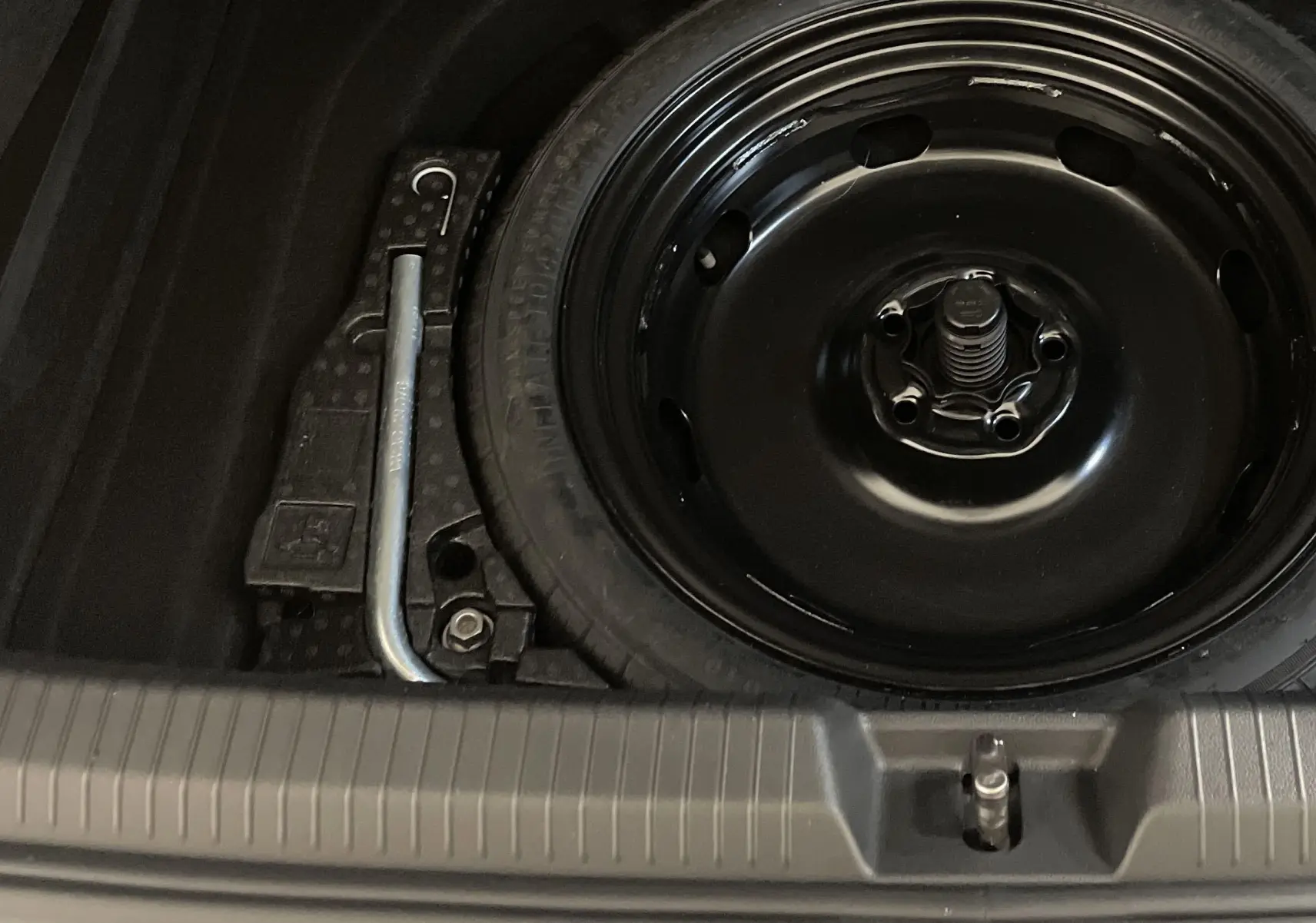 Gros plan sur la roue de secours noire et la clé de démontage dans le coffre d'une Volkswagen Golf 2.0 TDI 2022.