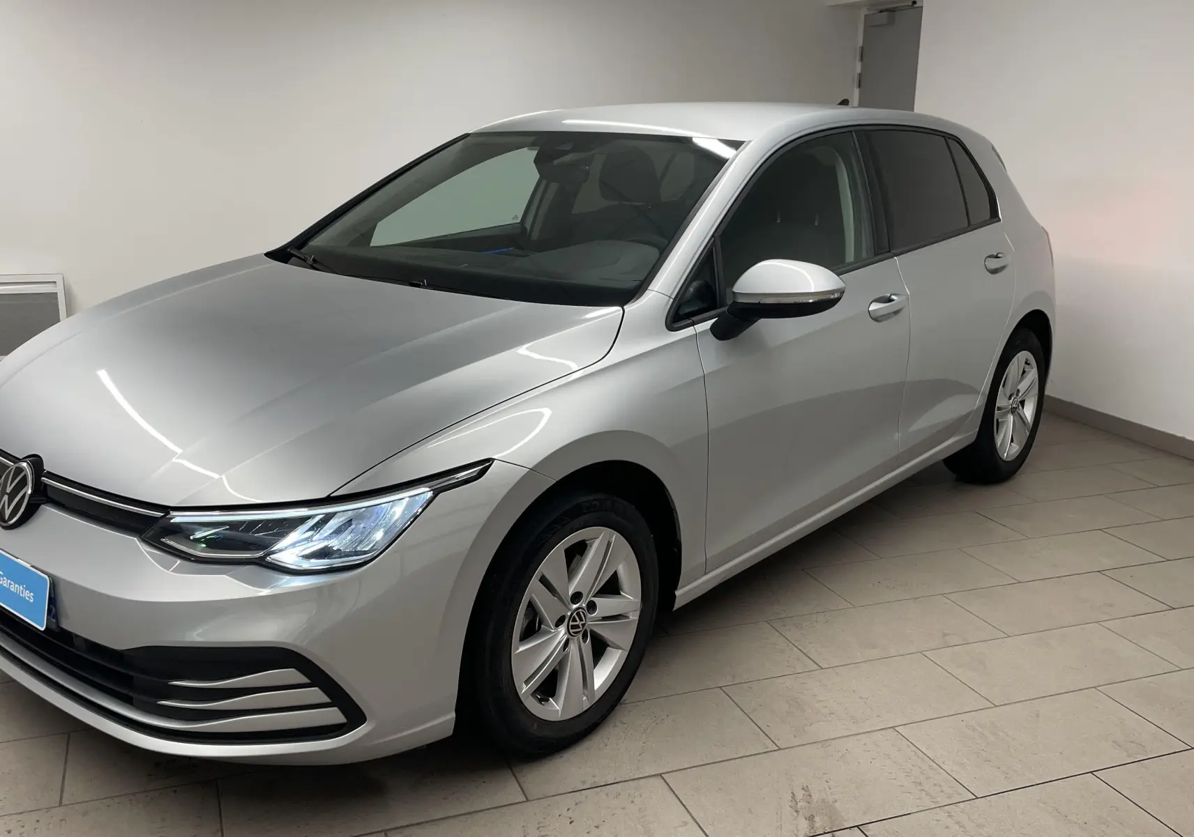 Volkswagen Golf 2.0 TDI 2022 en reflet d'argent vue 3/4 avant droit avec phares LED allumés et caméra de recul.
