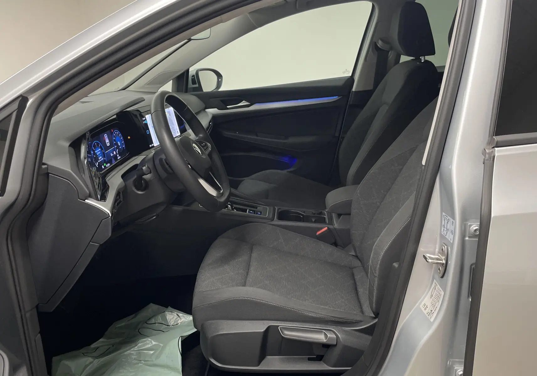 Intérieur avant côté conducteur de la Volkswagen Golf 2022 en reflet d'argent, avec tableau de bord numérique et sièges noirs.