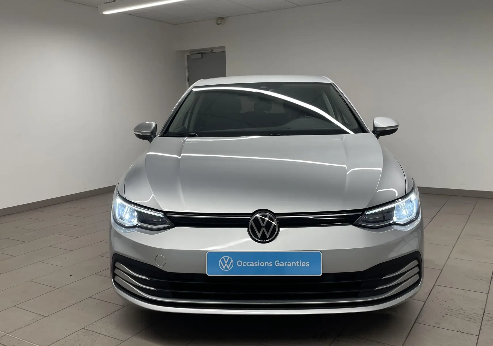 Volkswagen Golf 2.0 TDI 2022 en reflet d'argent vue de face avec phares allumés et plaque Occasions Garantis