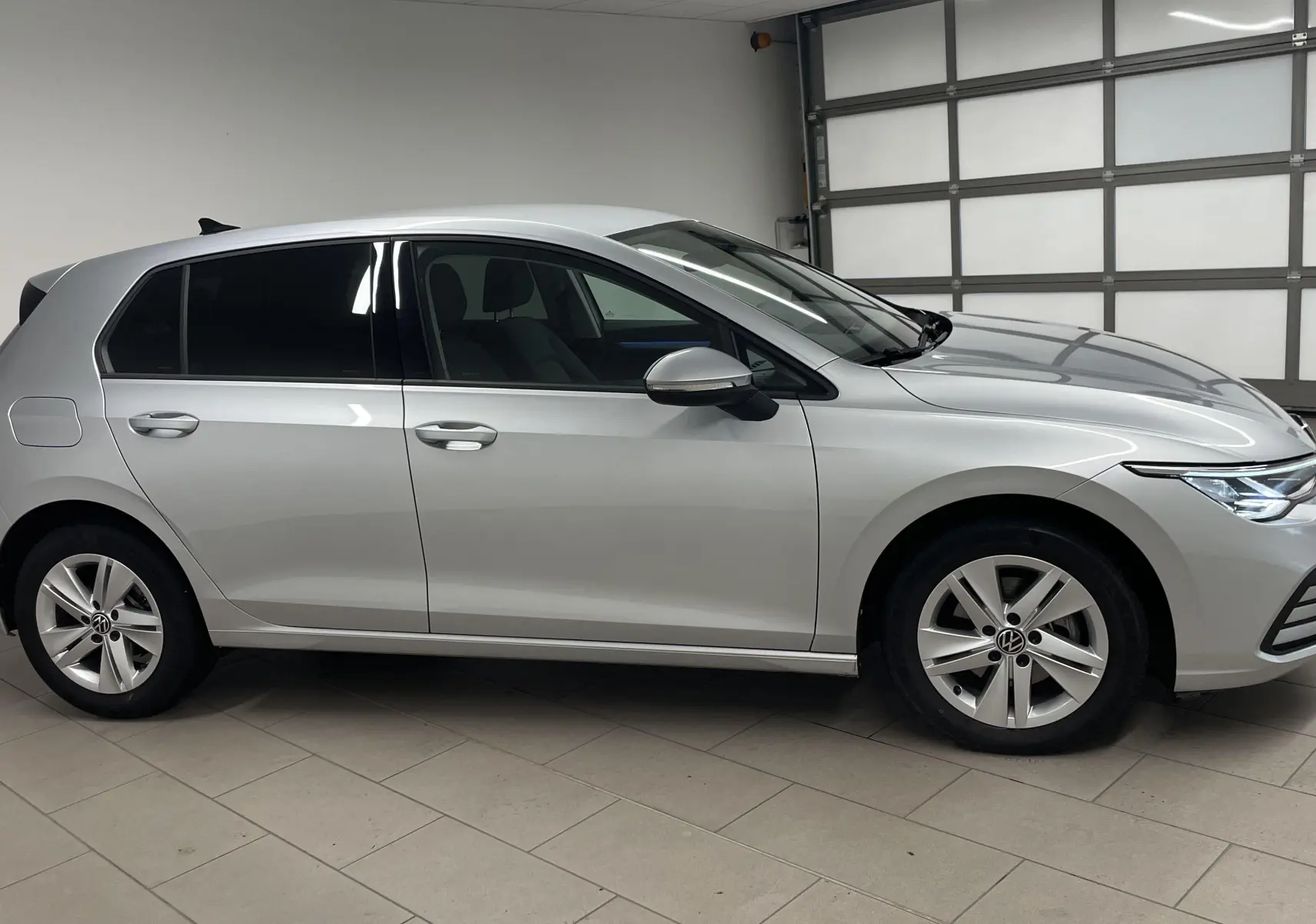 Profil côté gauche d'une Volkswagen Golf 2022 en peinture métallisée Reflet d'argent, avec jantes alliage et vitres teintées.