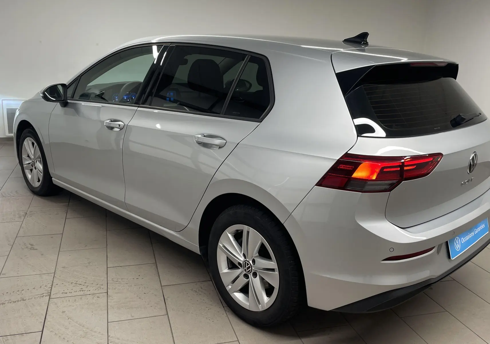 Volkswagen Golf 2.0 TDI 2022 en reflet d'argent, vue 3/4 arrière côté gauche avec feux arrière allumés.