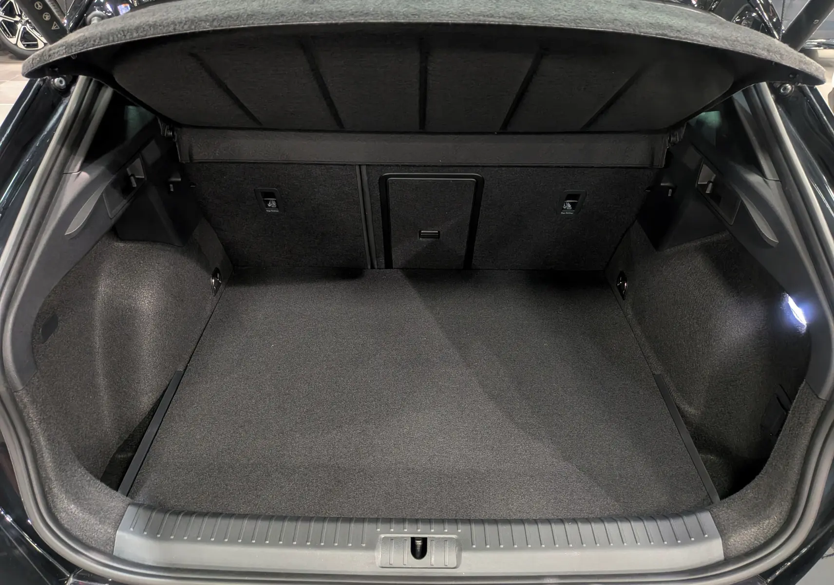 Coffre ouvert vu de l'arrière d'une CUPRA Formentor eHybrid noir minuit, montrant un espace de chargement propre et spacieux.