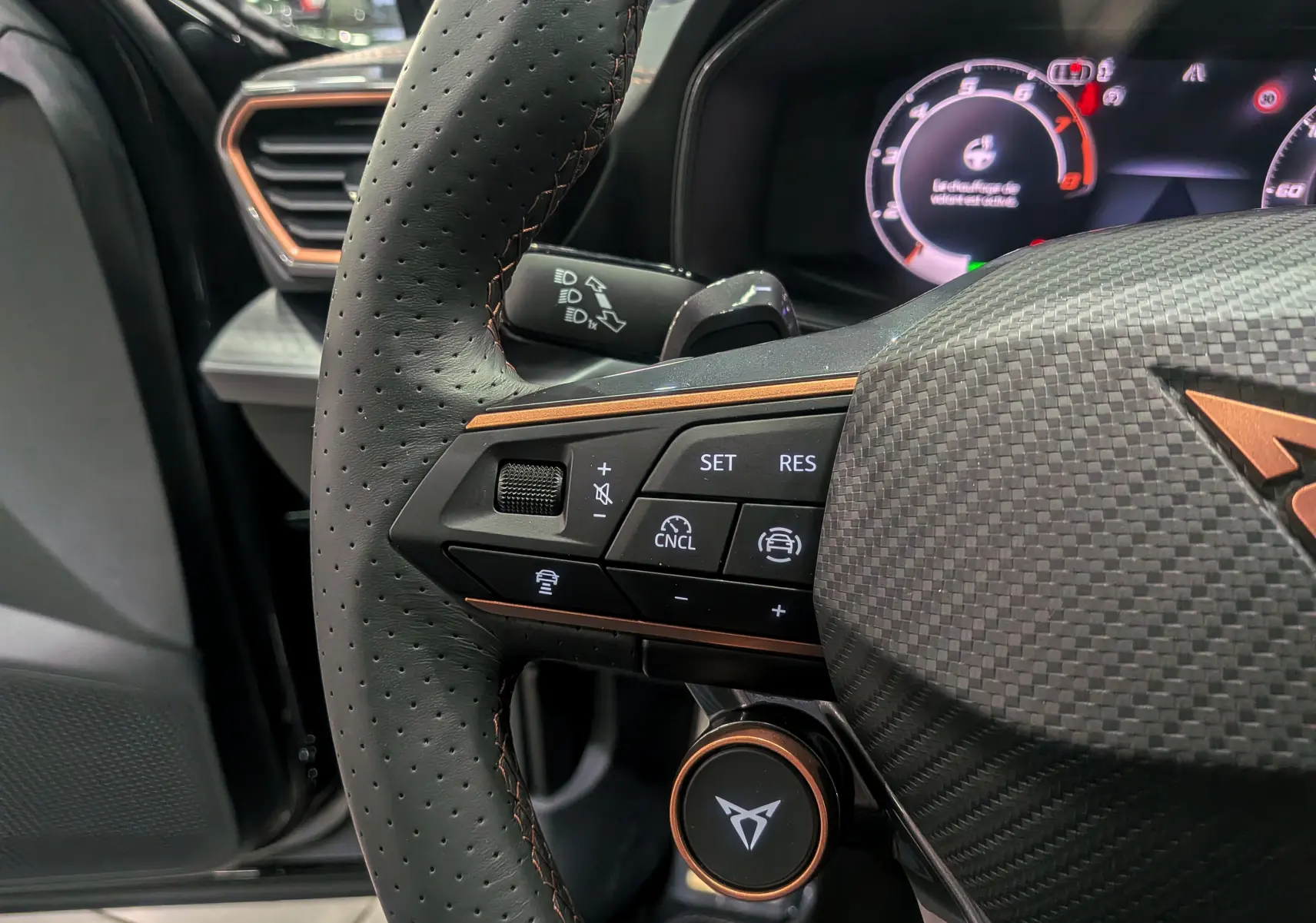 Gros plan sur le volant noir perforé avec détails cuivrés et commandes multifonctions du CUPRA Formentor eHybrid 2025.