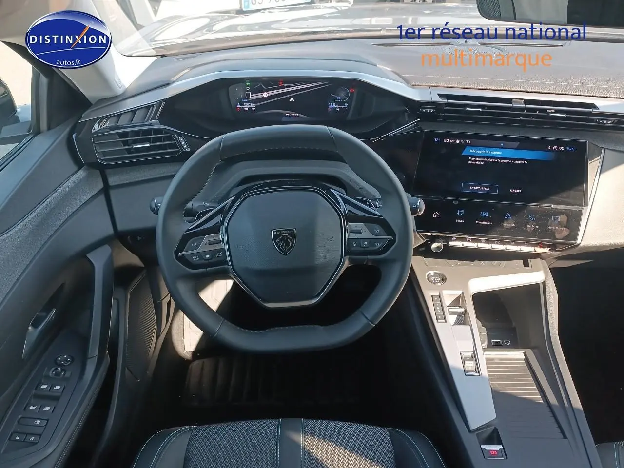 Vue intérieure frontale du poste de conduite du Peugeot 408 gris sélénite, avec volant cuir et écran tactile central.