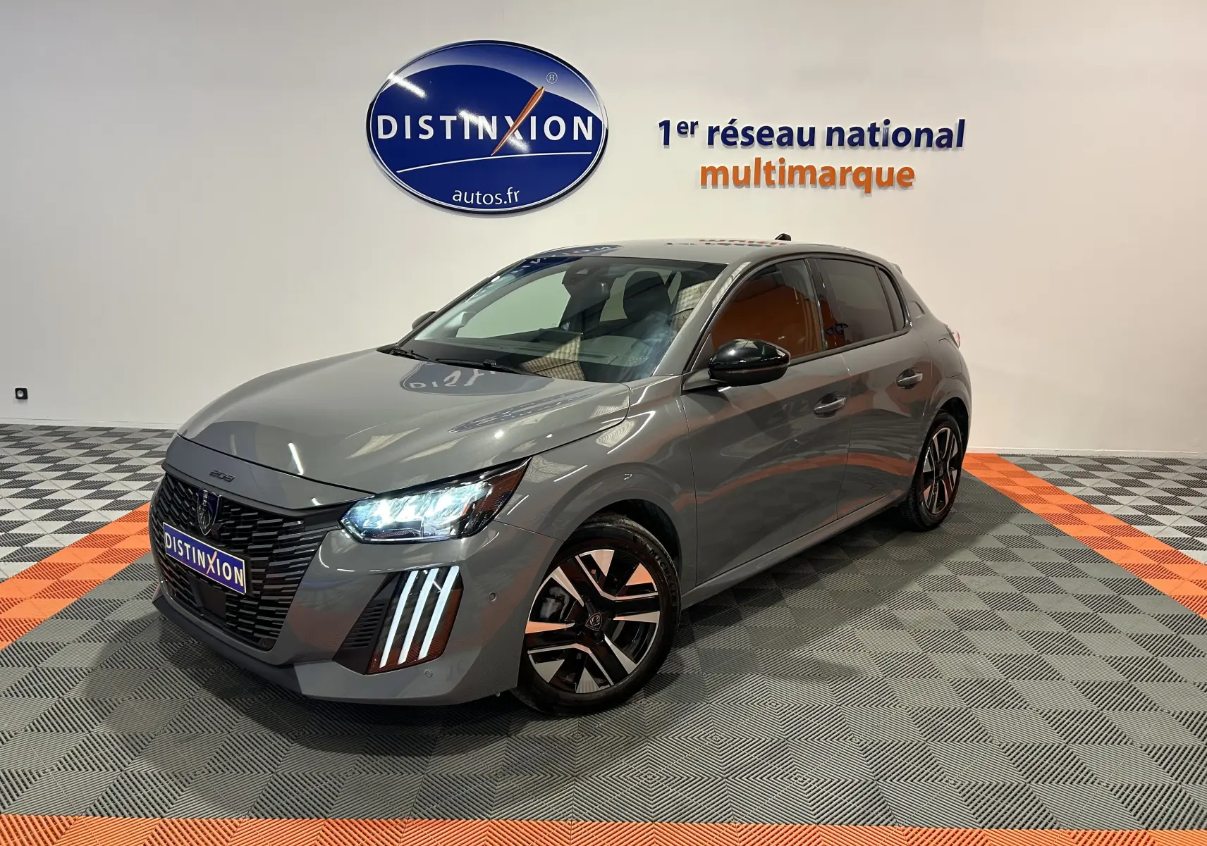 Peugeot 208 gris Selenium en 3/4 avant droit, phare LED allumé et jantes alliage distinctives.