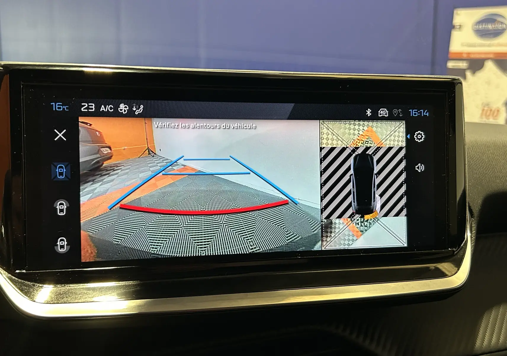 Écran central de la Peugeot 208 gris Selenium montrant la caméra 360° avec vue arrière et top-down du véhicule.