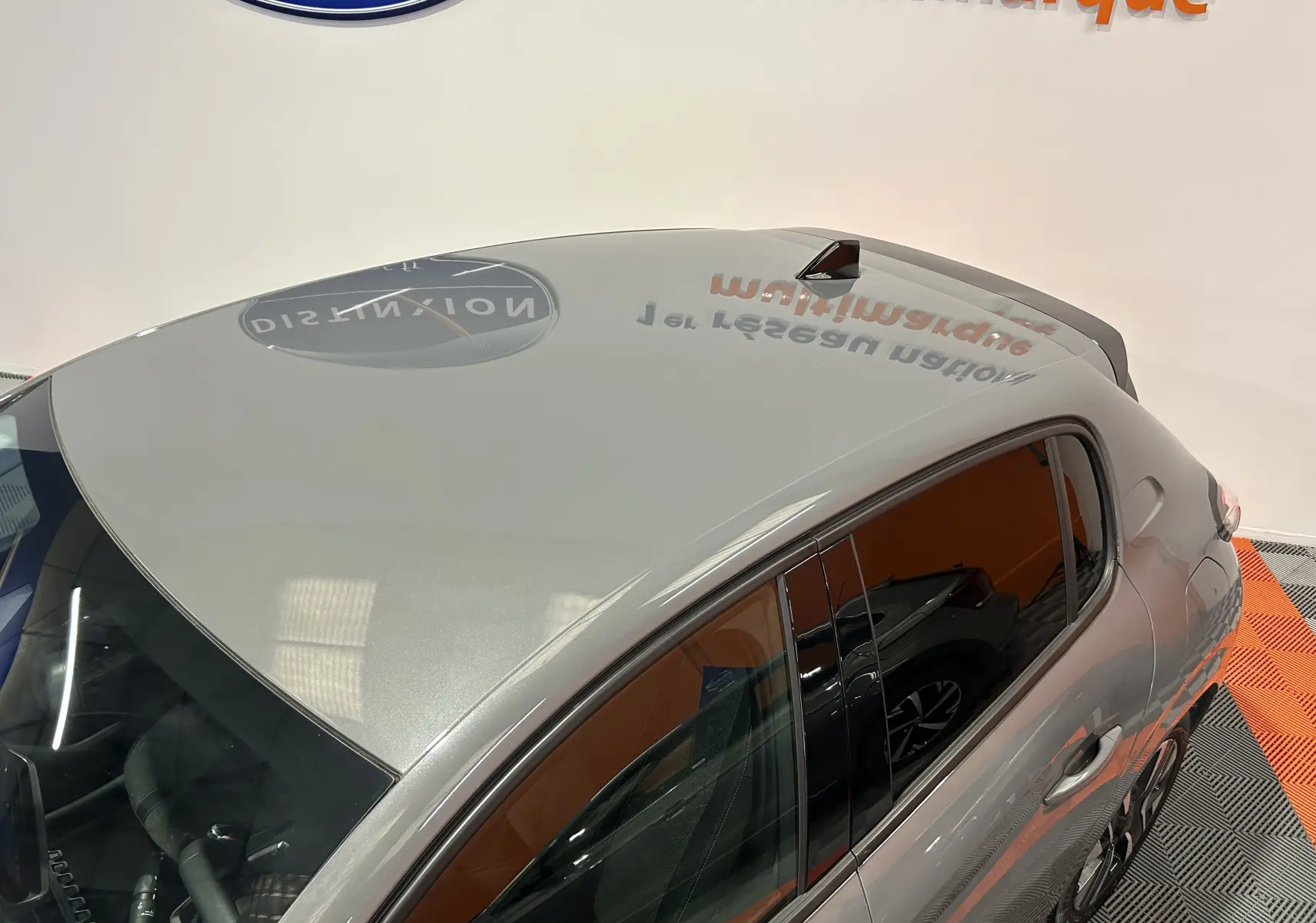 Vue plongeante sur l'arrière droit d'une Peugeot 208 gris Selenium, mettant en valeur la ligne de toit et les vitres teintées.