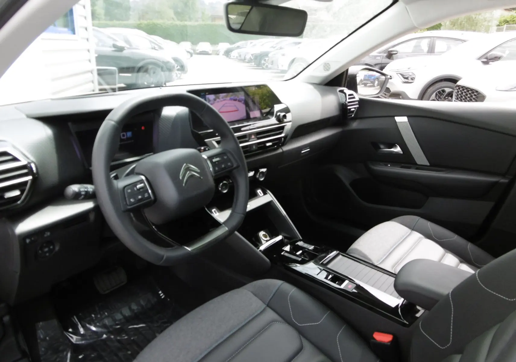 Intérieur moderne de Citroën C4 X blanc polaire, vue côté conducteur avec tableau de bord digital et volant multifonction.