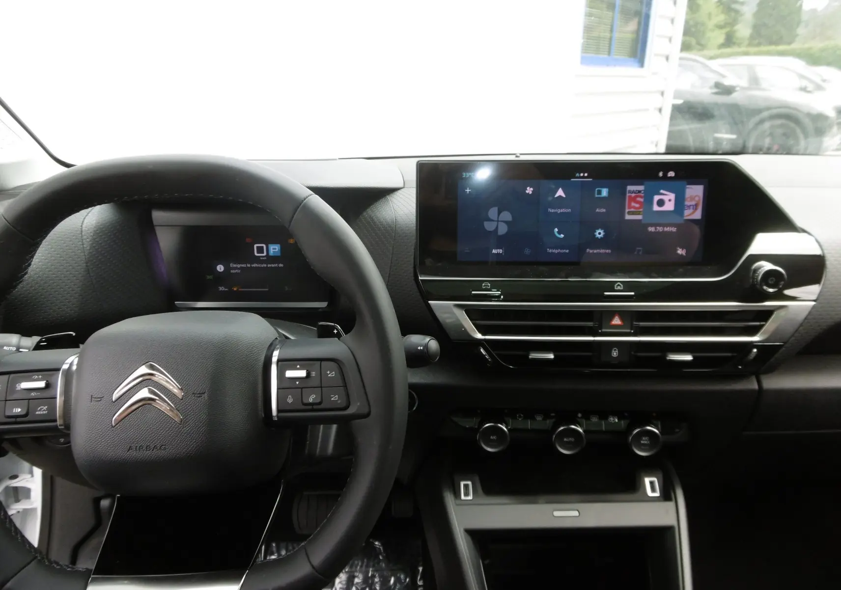 Intérieur de la Citroën C4 X 2023, vue du tableau de bord avec écran tactile et volant multifonction noir.