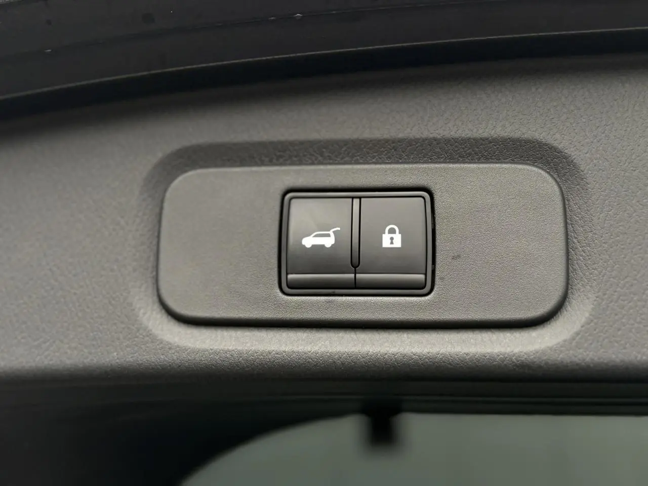 Gros plan sur les boutons du hayon électrique et de verrouillage intérieur du Nissan Qashqai gris Squale 2024.