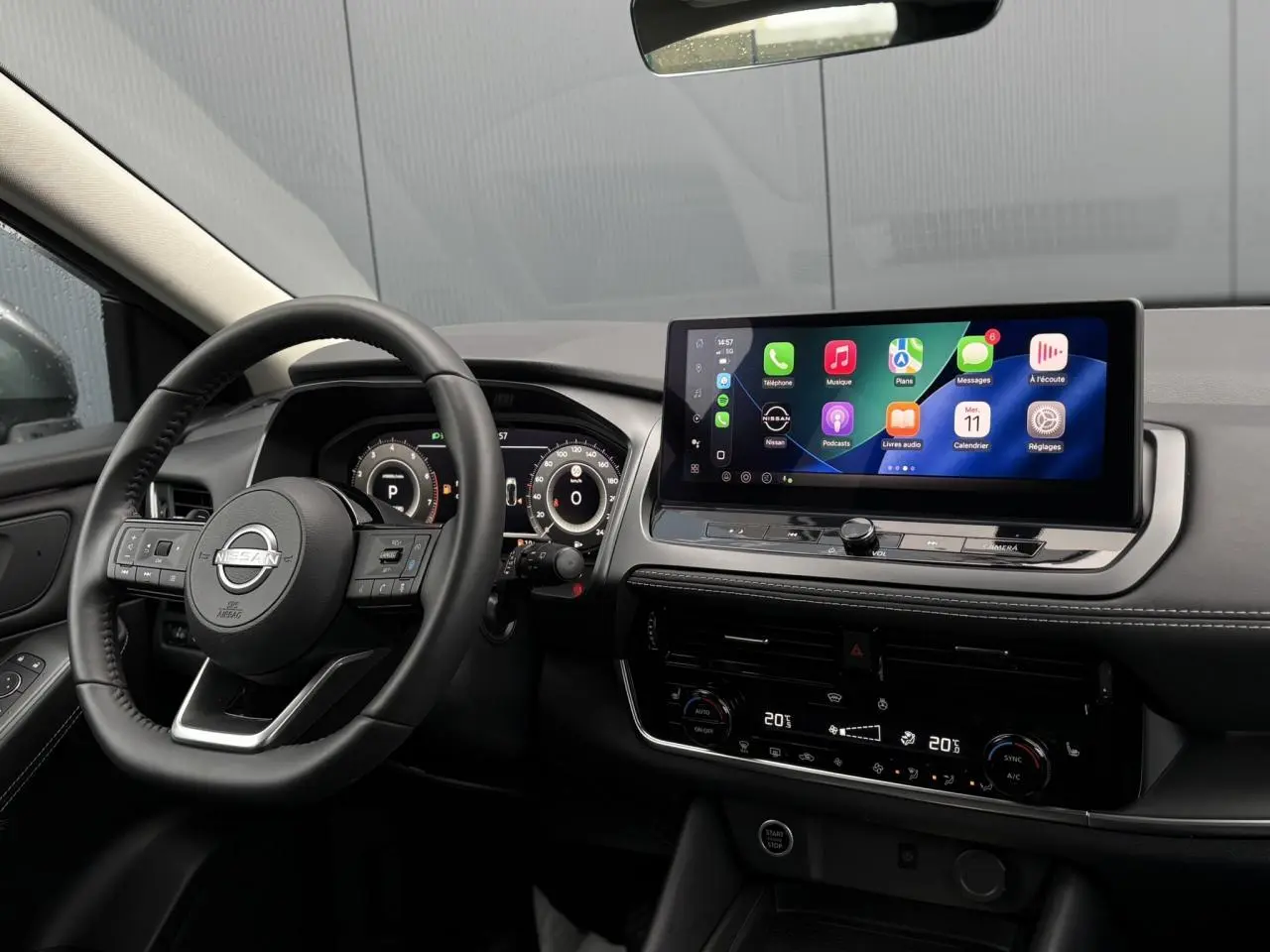 Vue intérieure du tableau de bord et volant noir du Nissan Qashqai 2024 avec écran tactile large et affichage numérique.