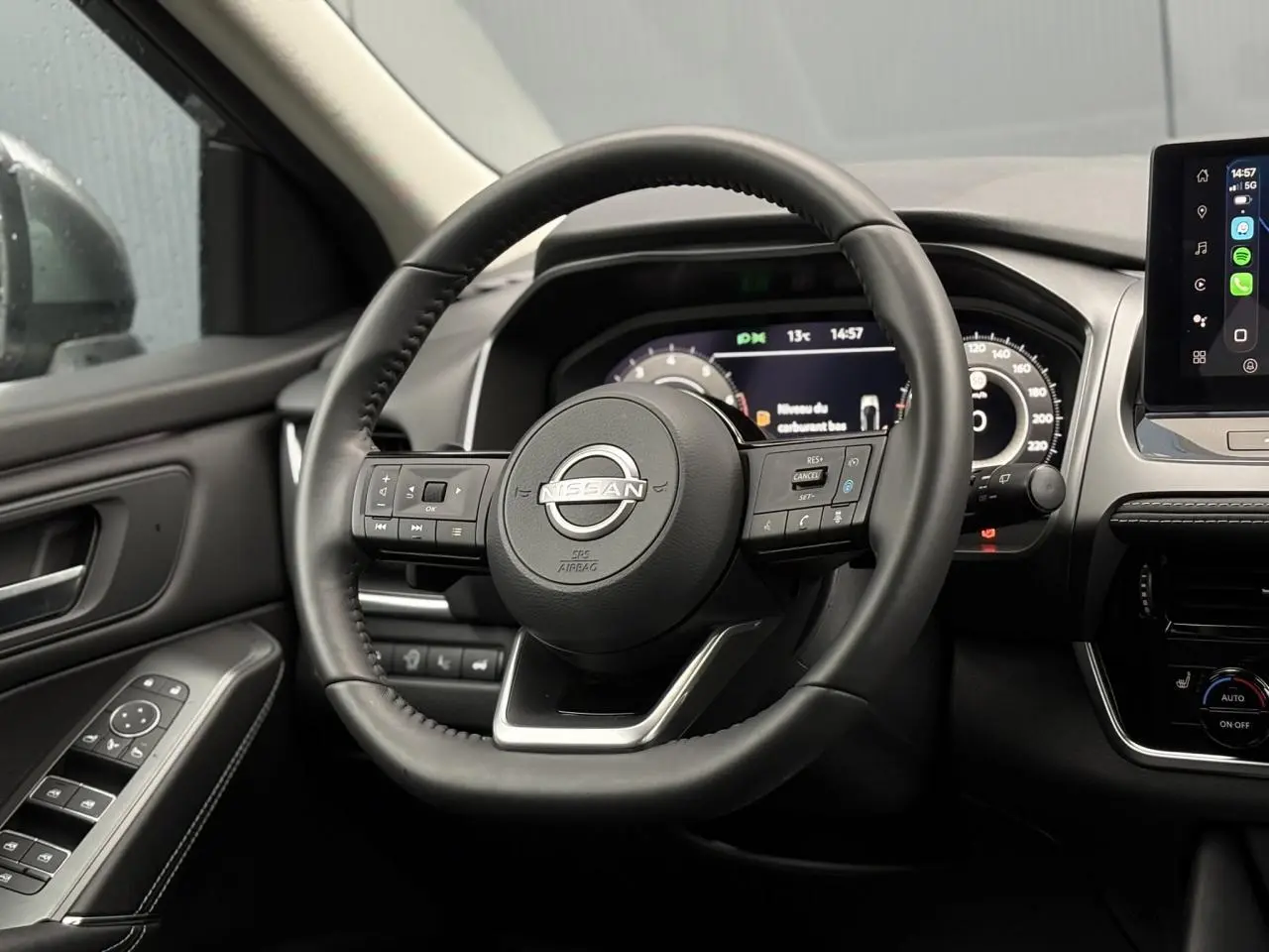 Vue intérieure centrée sur le volant cuir noir du Nissan Qashqai 2024 avec tableau de bord numérique et écran tactile.