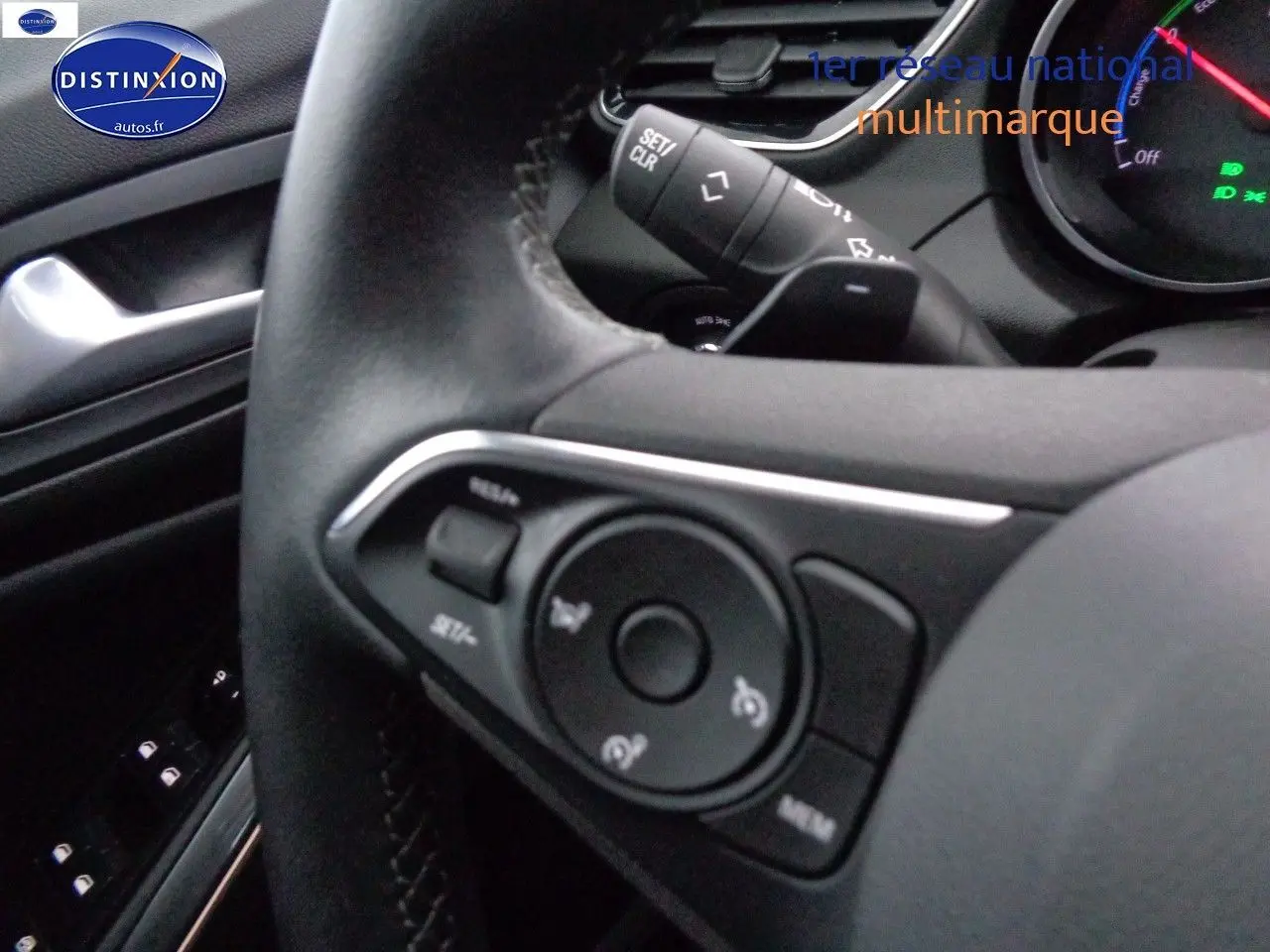 Gros plan sur le volant noir de l'Opel Grandland X 1.6 Hybrid Turbo 2021, avec commandes intégrées visibles.