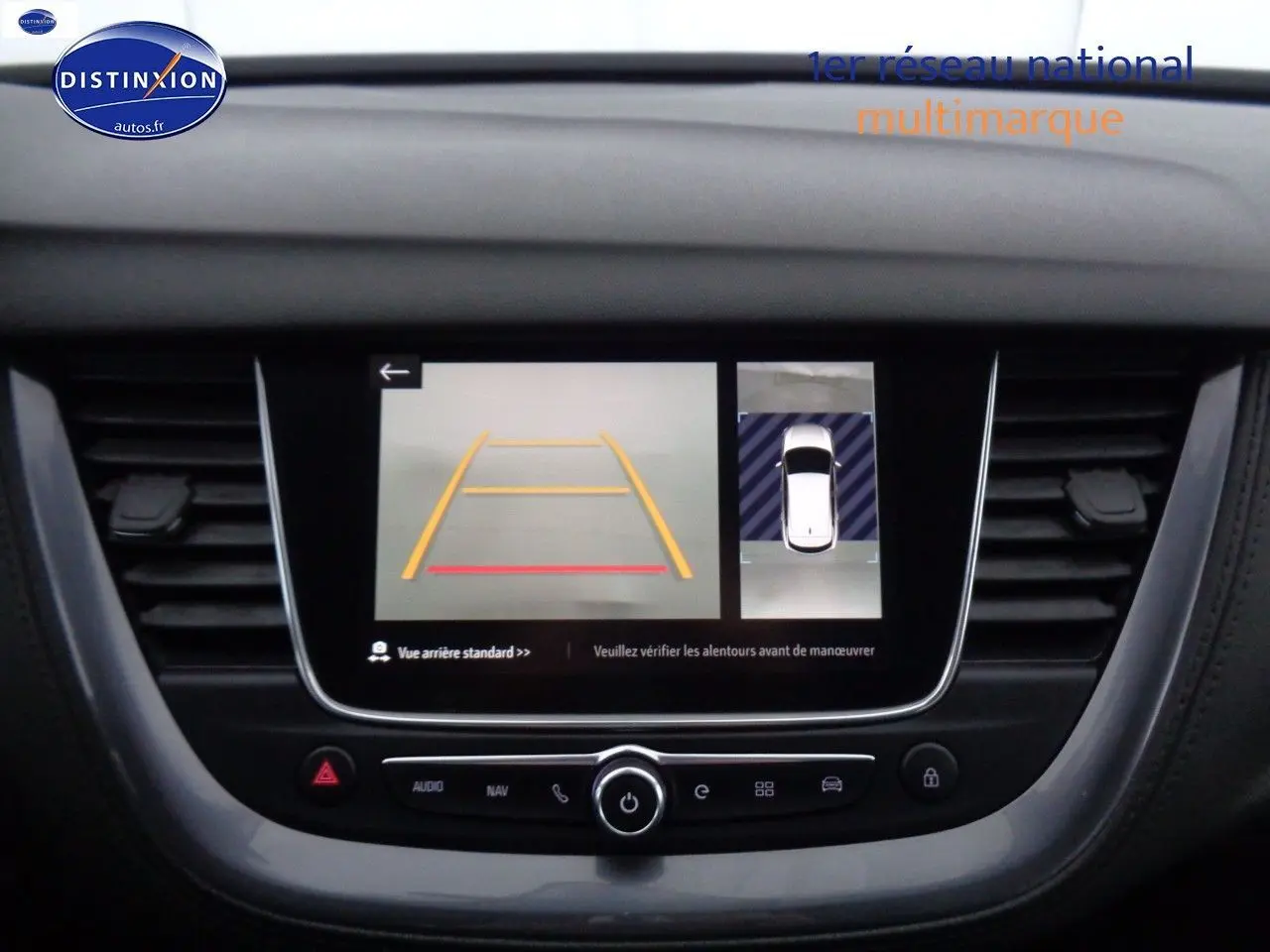 Écran central de l’Opel Grandland X blanc nacré montrant la caméra de recul et l’aide au stationnement en vue intérieure.