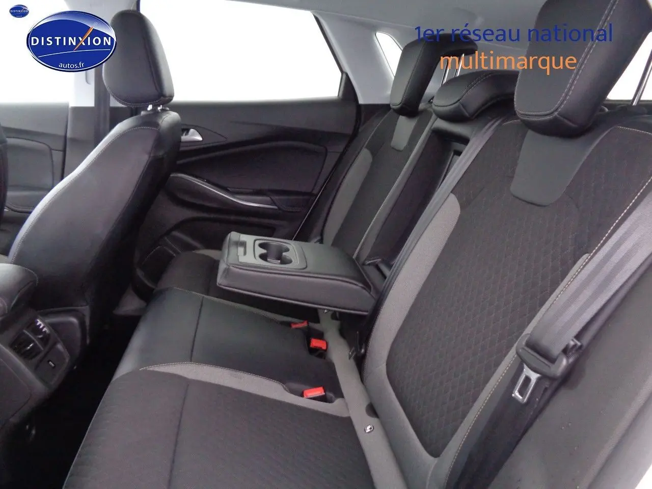 Vue intérieure sur les sièges arrière en tissu noir et gris avec accoudoir central baissé de l'Opel Grandland X blanc nacré.