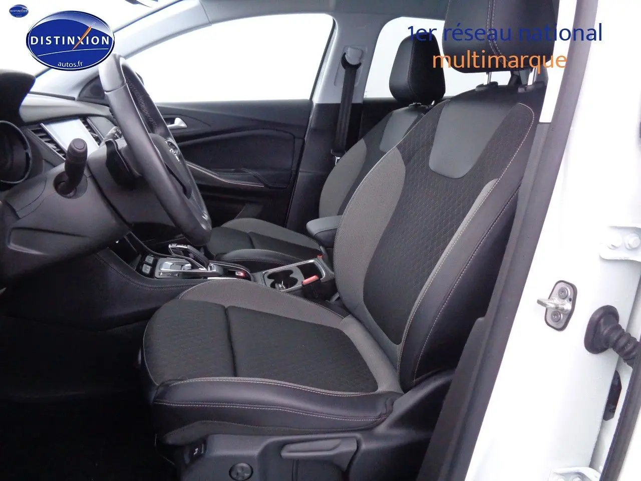 Vue intérieure côté conducteur de l'Opel Grandland X blanc nacré, sièges tissu et cuir noir avec console centrale visible.