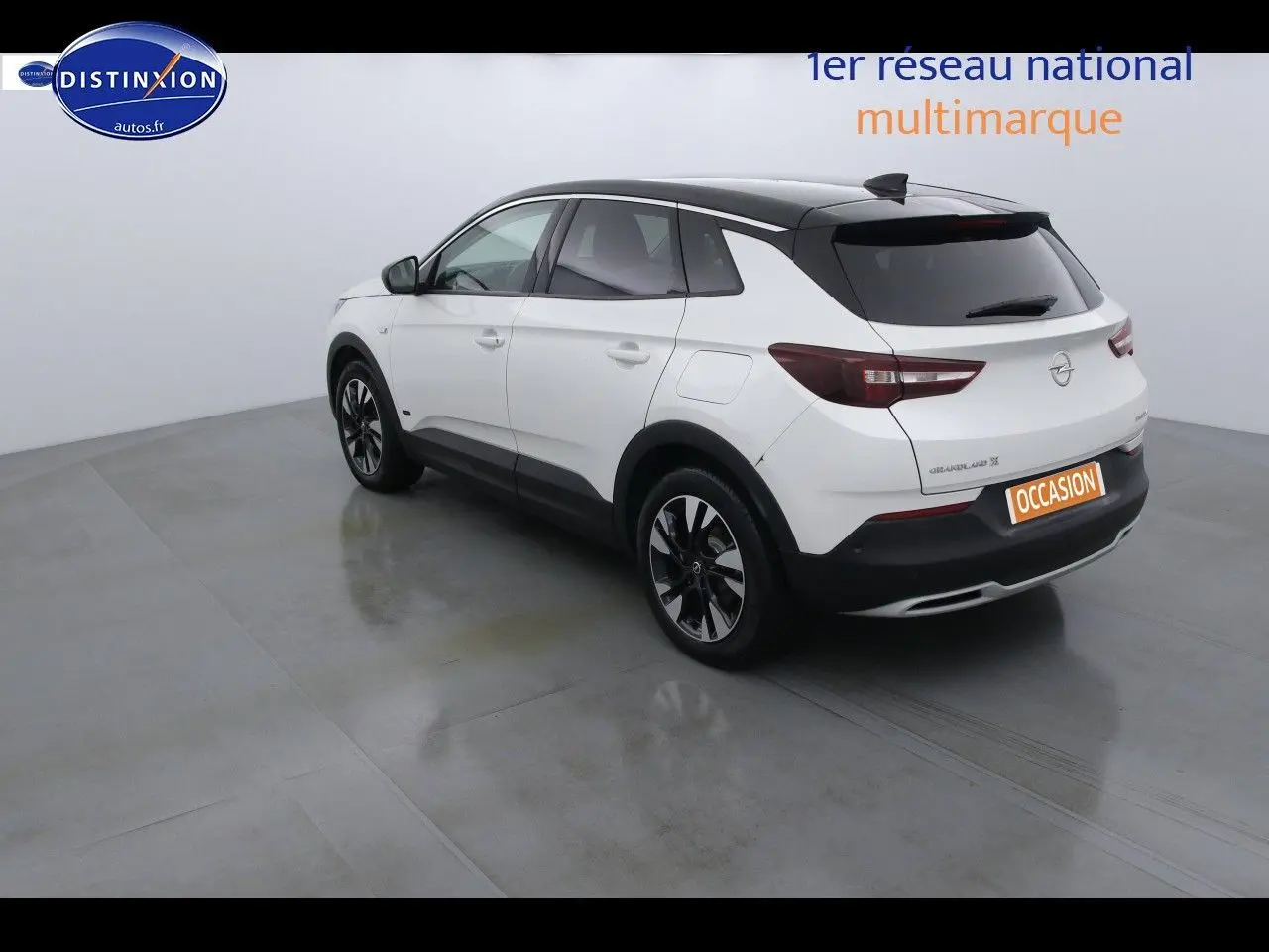 Vue 3/4 arrière droite d'un Opel Grandland X blanc nacré avec toit noir et jantes alliage noires.