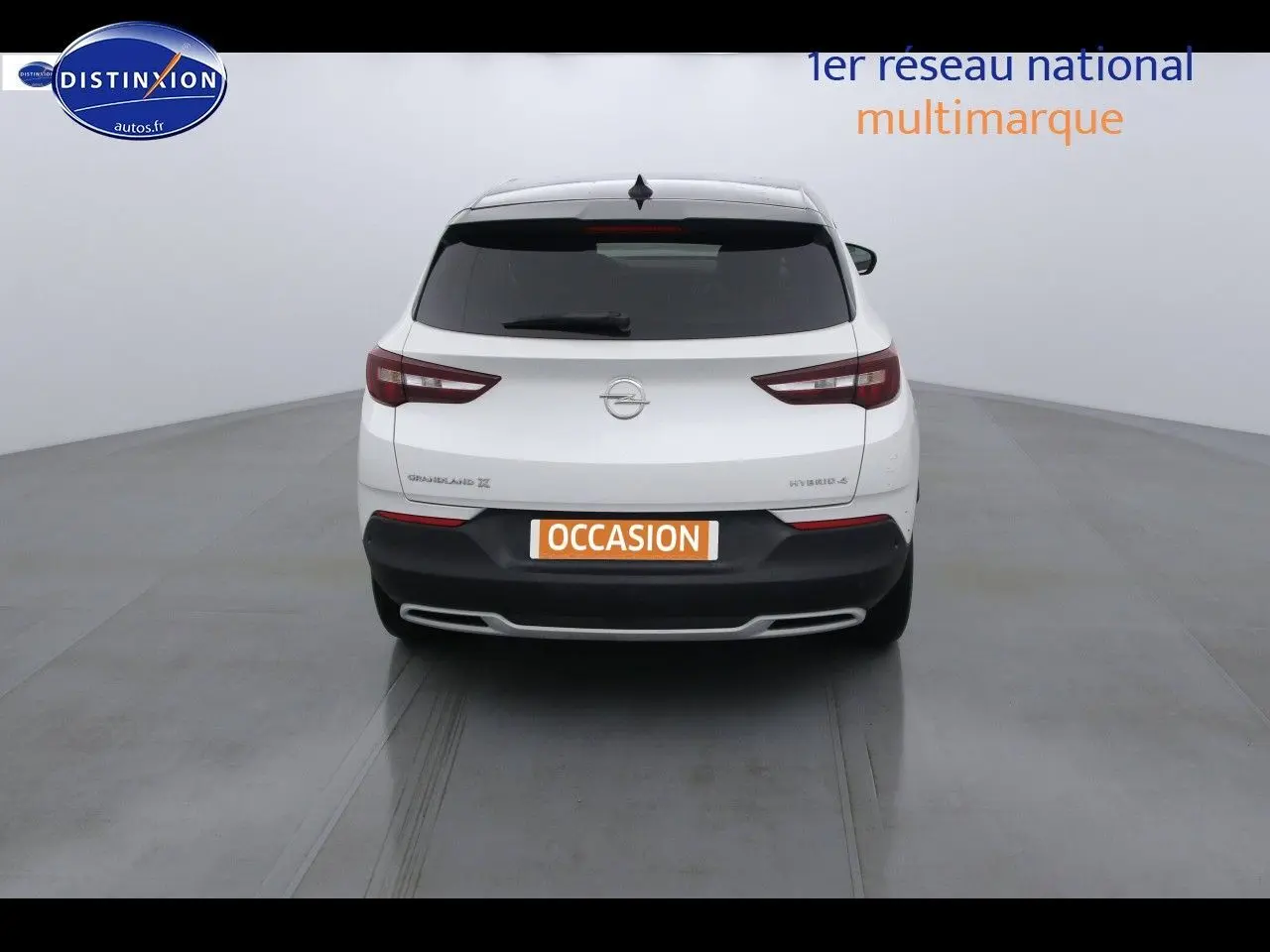 Vue arrière d'un Opel Grandland X hybride blanc nacré, avec hayon fermé et feux arrière allongés distinctifs.