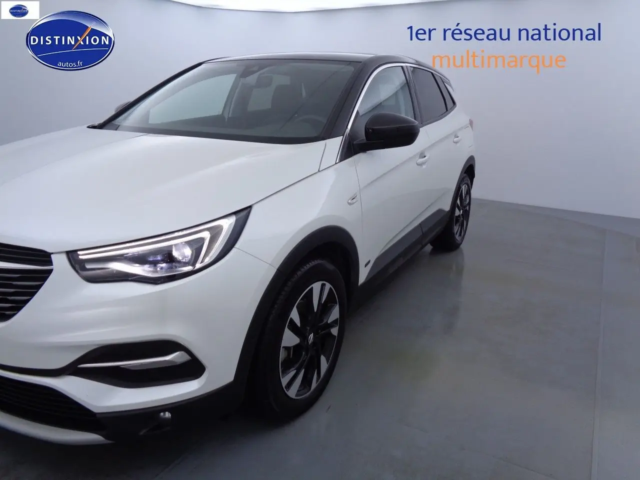 Opel Grandland X blanc nacré, vue 3/4 avant droit, avec jantes alliage noires et phares LED allumés.