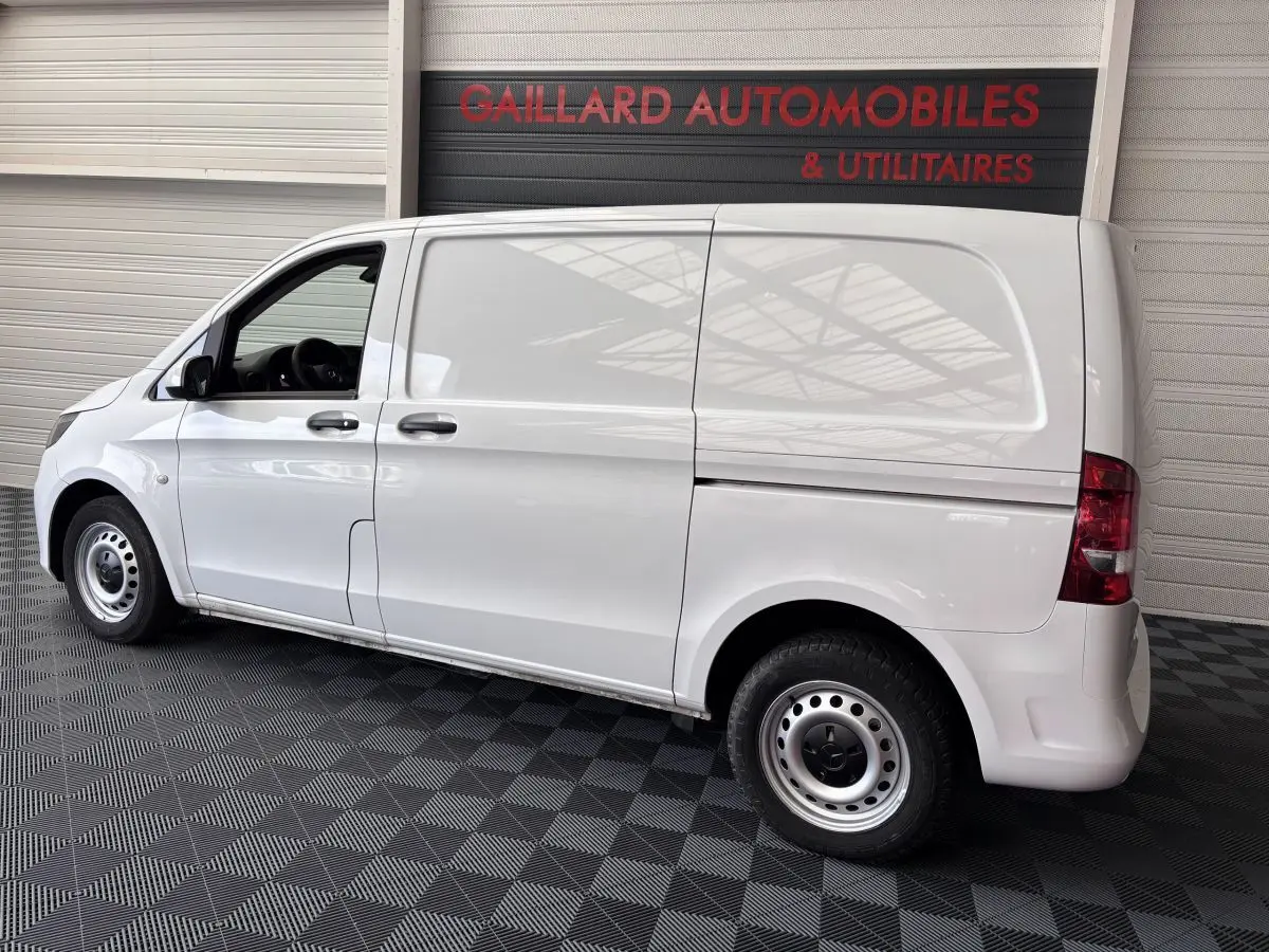 Vue latérale droite d'un utilitaire Mercedes Vito 111 CDI Compact blanc avec deux portes et hayon, en intérieur showroom.